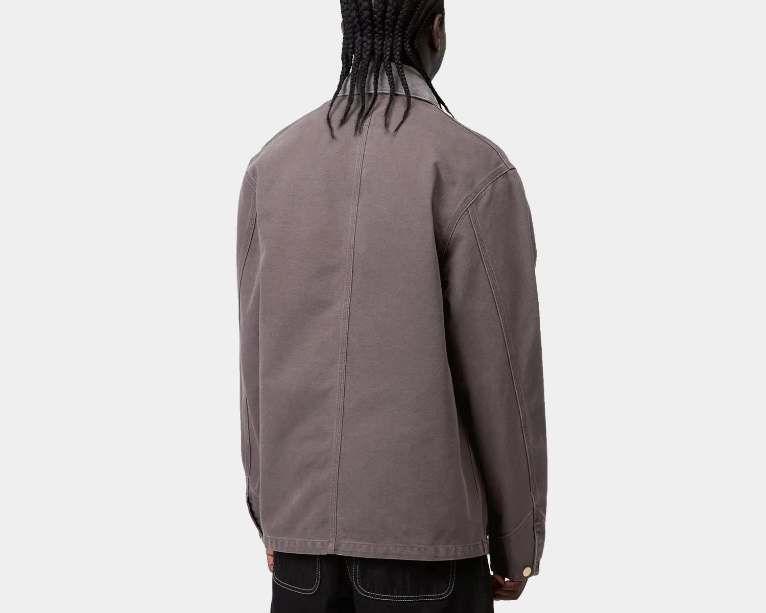Back view of a person wearing a gray long-sleeve jacket with visible seam details and black pants with white stitching.