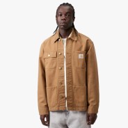 Brown Carhartt work jacket with four front pockets and snap buttons worn by a person.