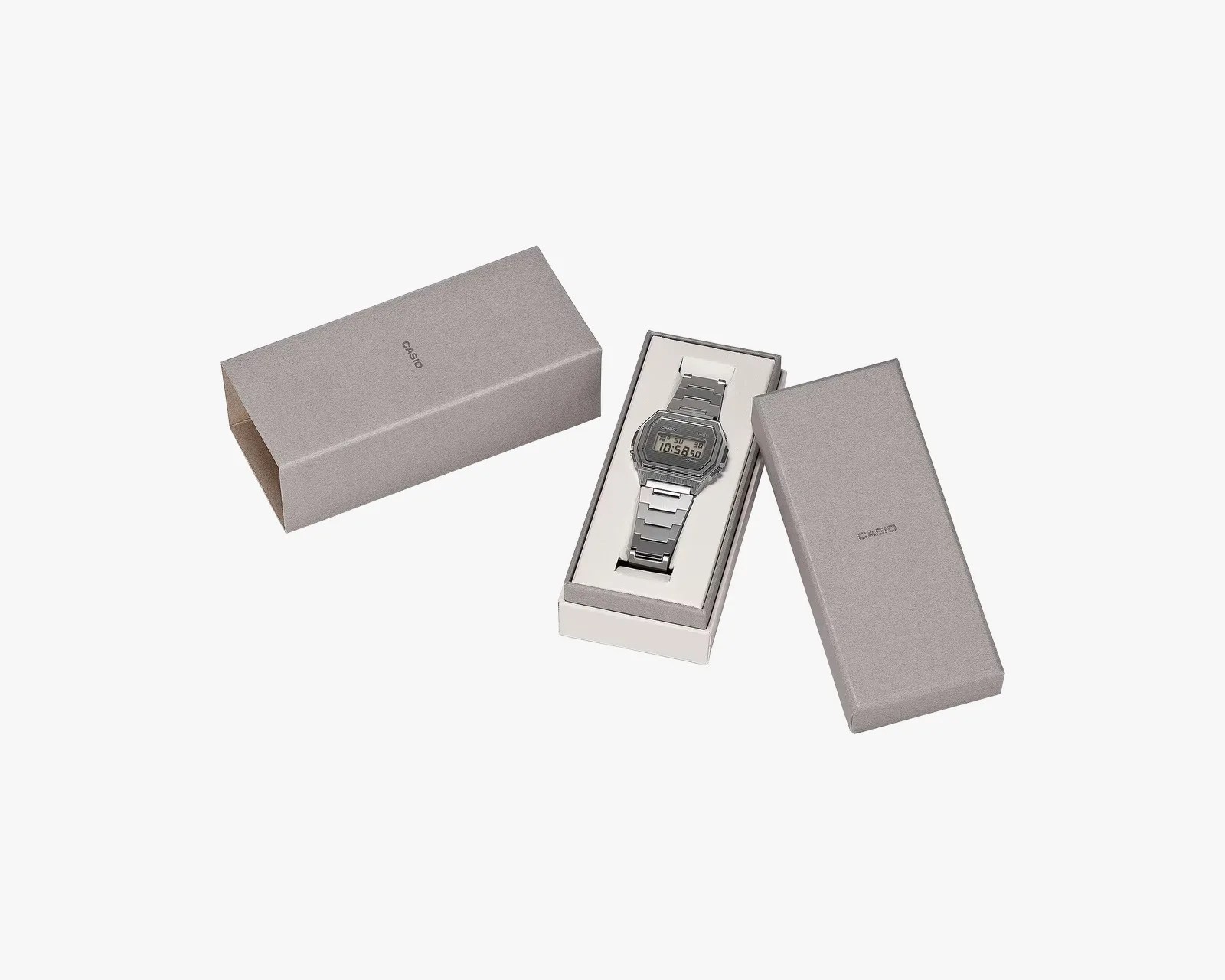 Silver Casio digital watch with metal band in an open gray Casio box with lid beside it.