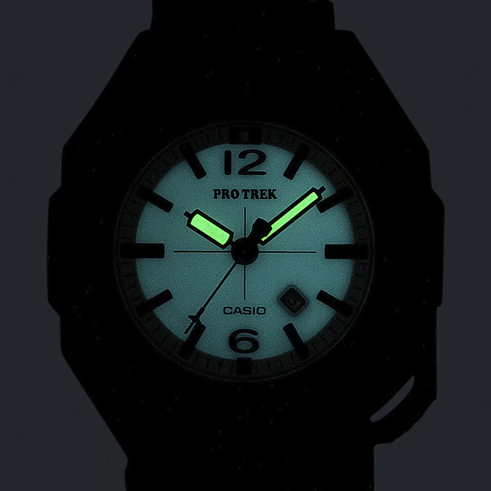 Close-up of a Casio Pro Trek watch face glowing in the dark with luminous hour and minute hands.