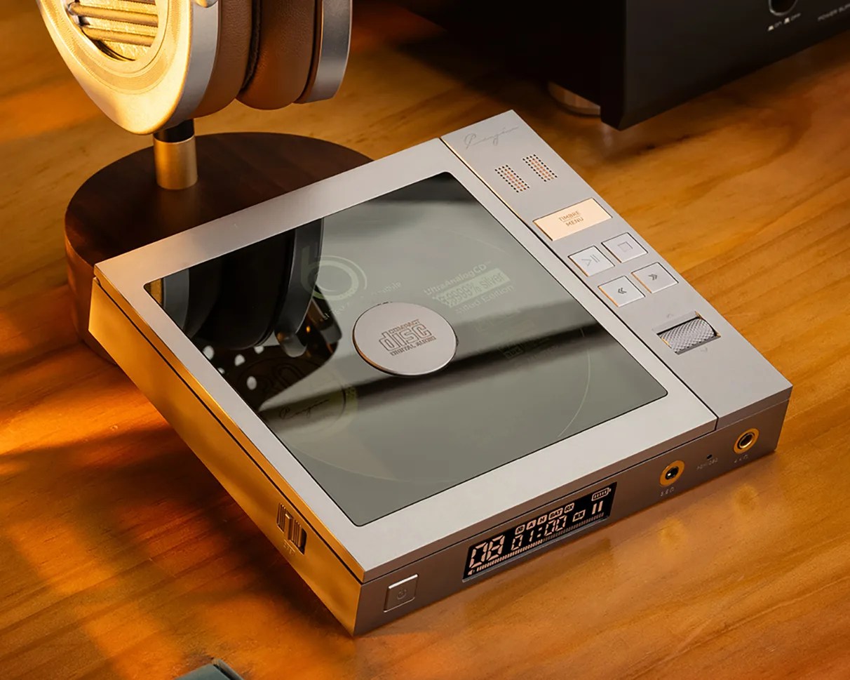 Silver portable CD player with a transparent lid, control buttons, and a digital display on a wooden surface.