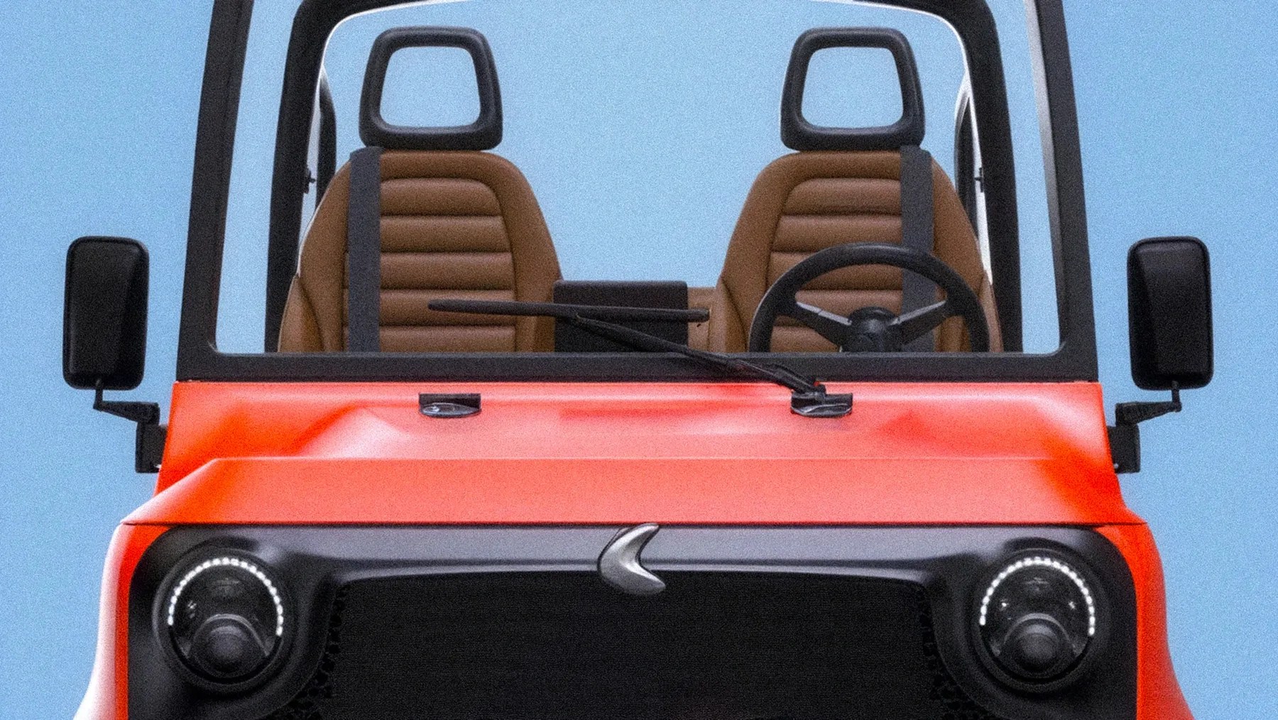 Front view of a small orange vehicle with two brown seats, black steering wheel, and round headlights.