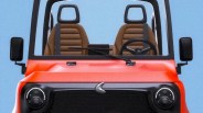 Front view of a small orange vehicle with two brown seats, black steering wheel, and round headlights.