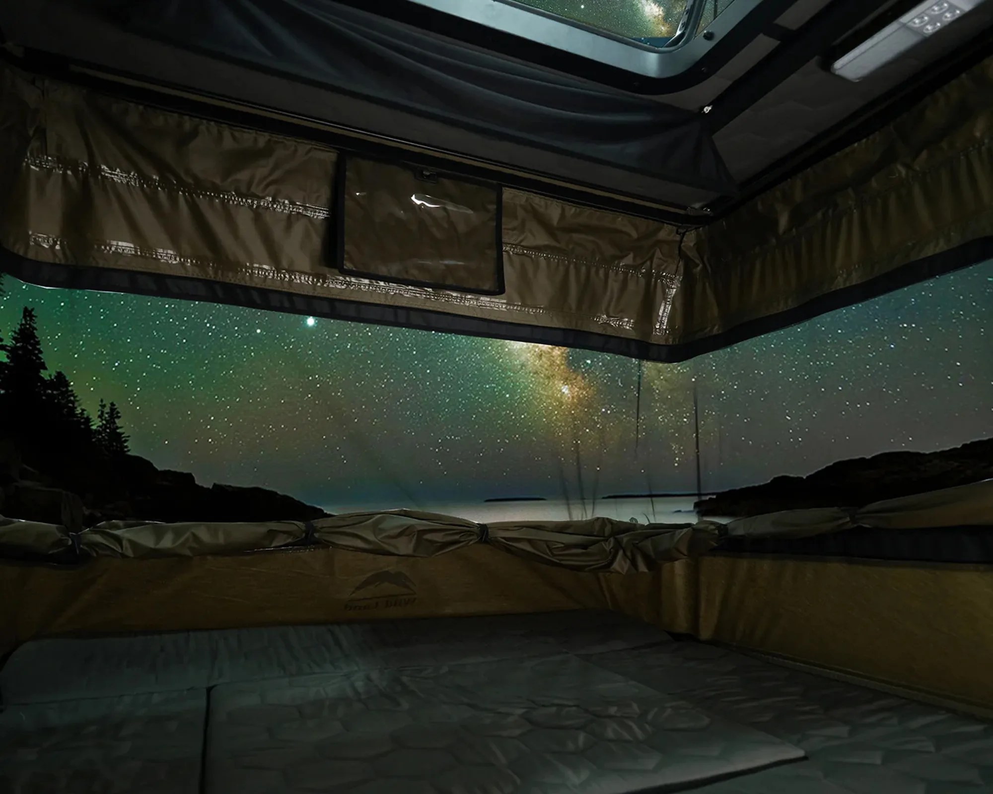 Interior view of a rooftop tent with brown fabric walls and mattress under a starry night sky.
