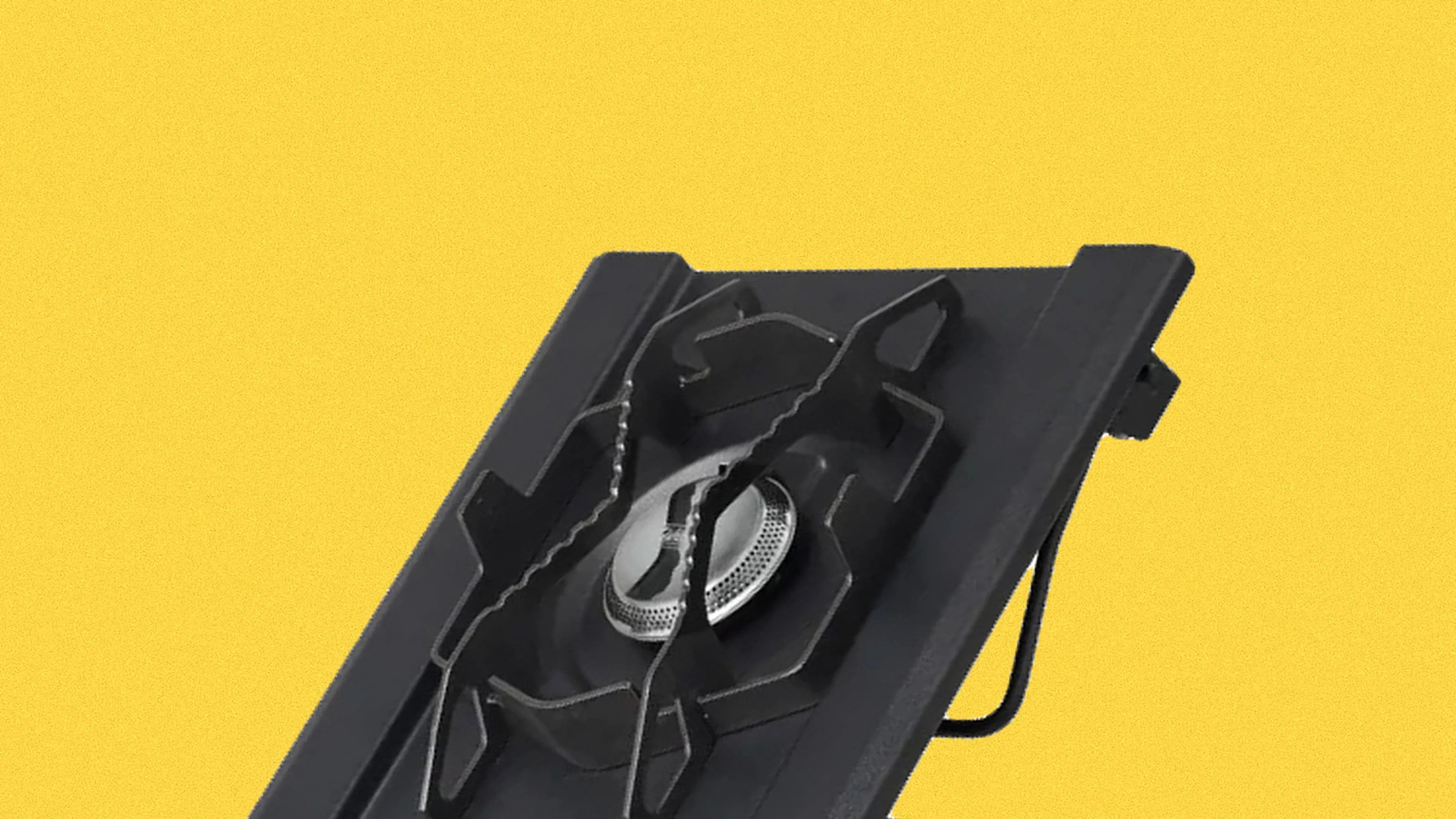 Black single-burner gas stove with metal grate on a yellow background.