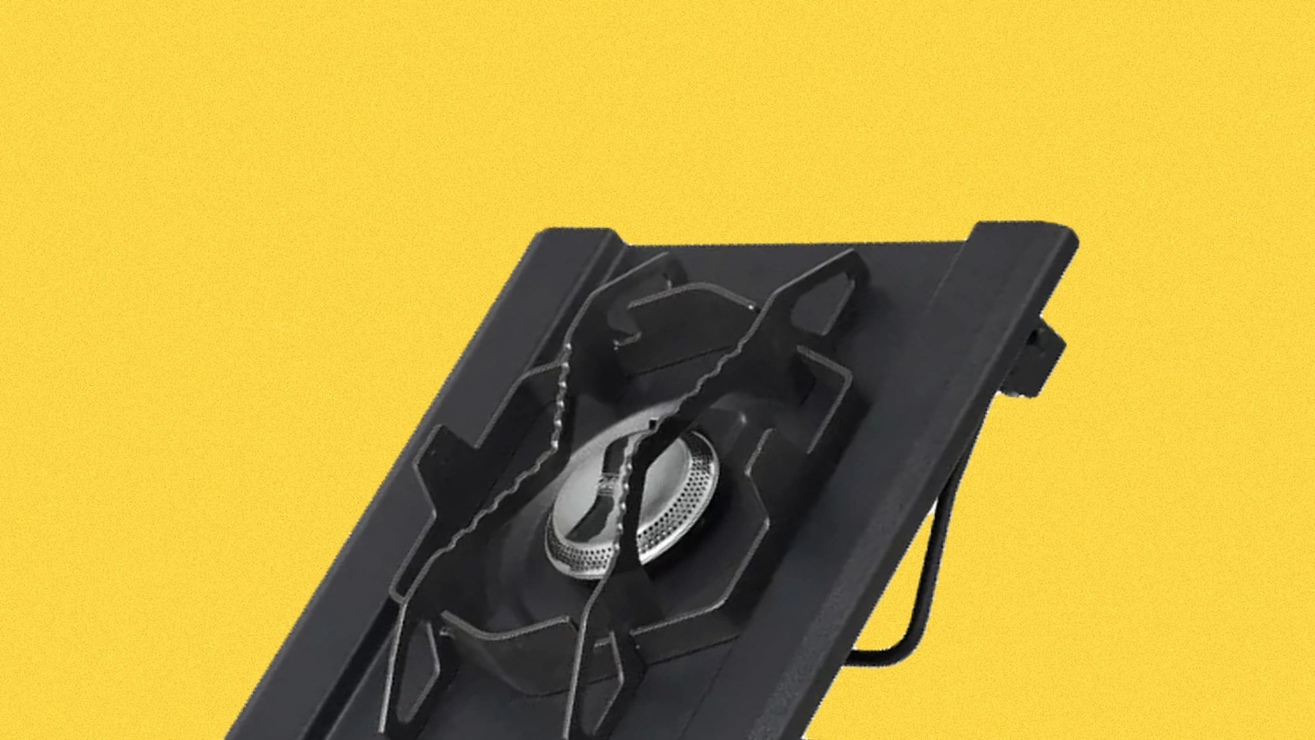 Black single-burner gas stove with metal grate on a yellow background.
