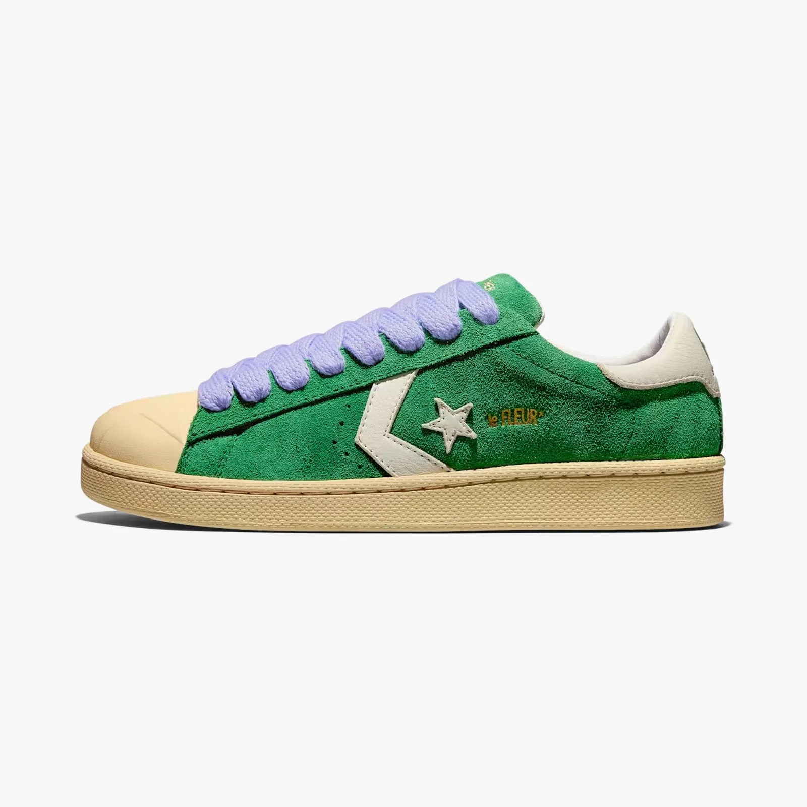Green suede Converse sneaker with white star logo, beige toe cap and sole, and lavender laces.