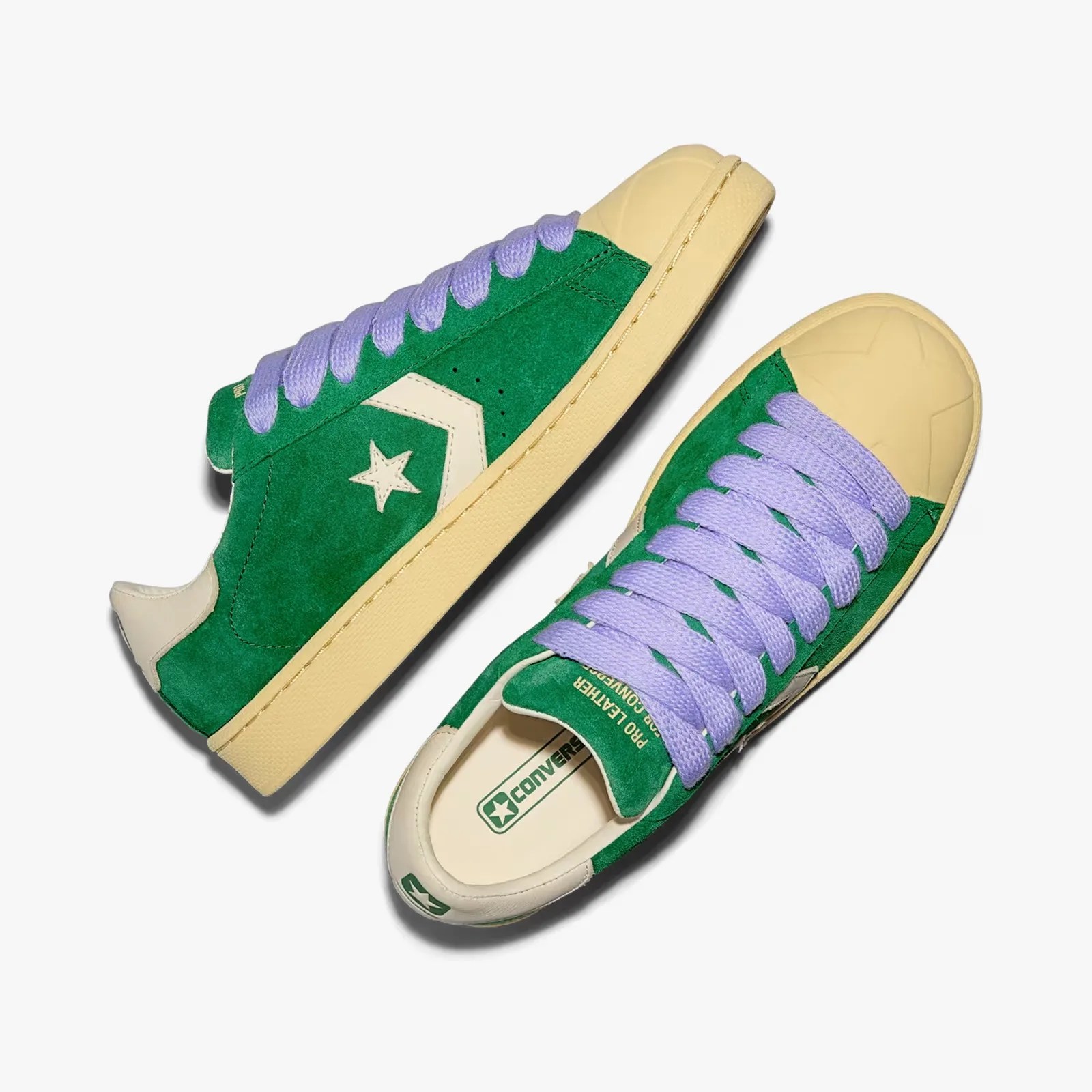 Green suede Converse sneakers with cream rubber toe caps and lavender laces.
