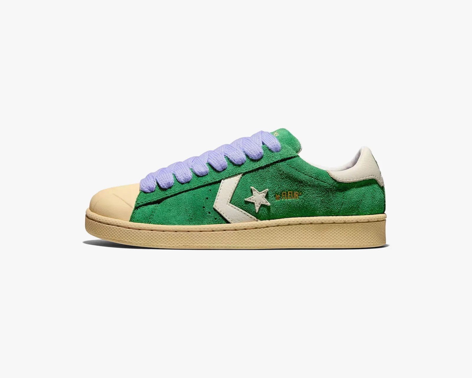 Green suede low-top sneaker with beige toe cap, sole, white star logo, and lavender laces.