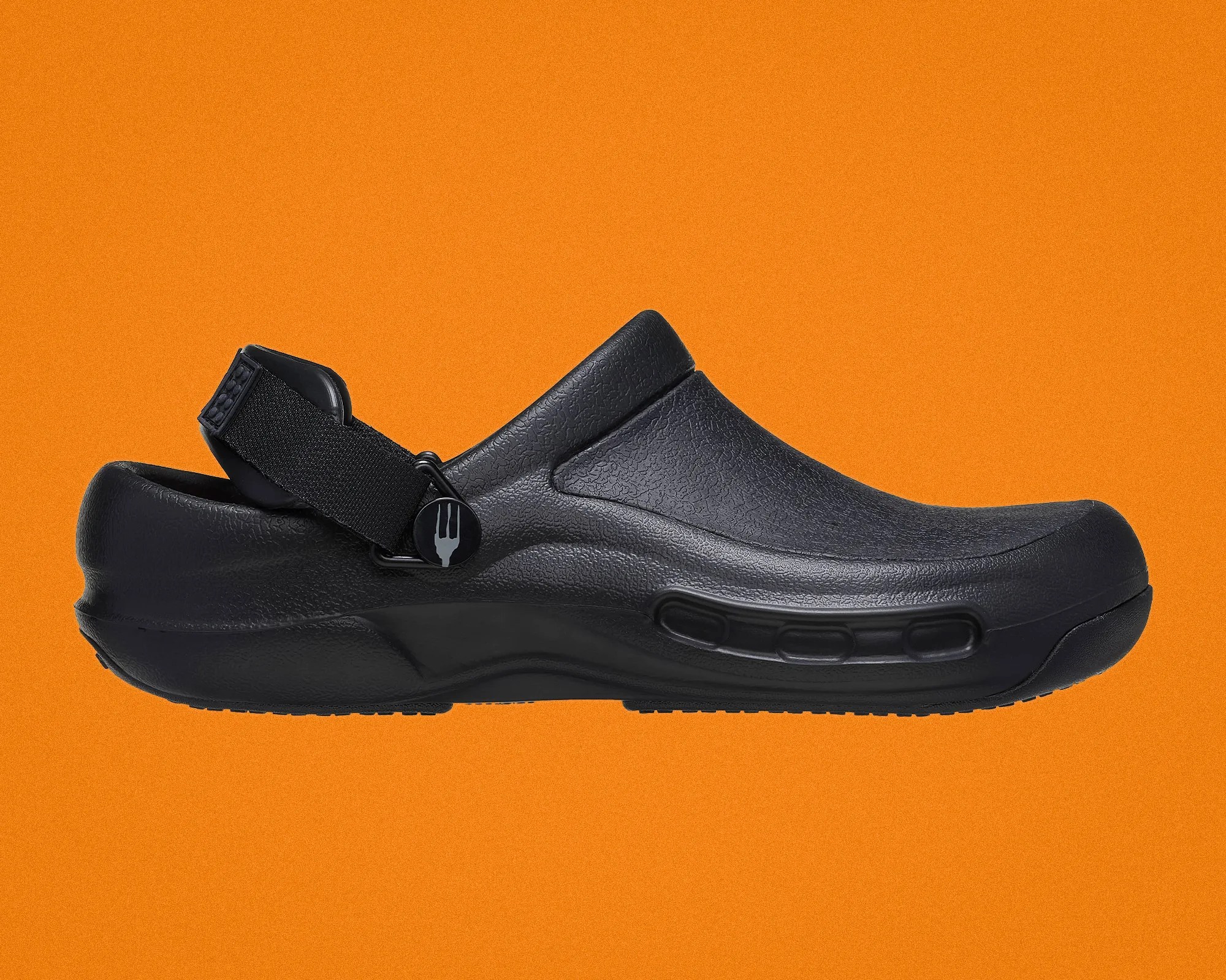 Black textured slip-on clog with adjustable black strap and fork logo on strap button, against an orange background.
