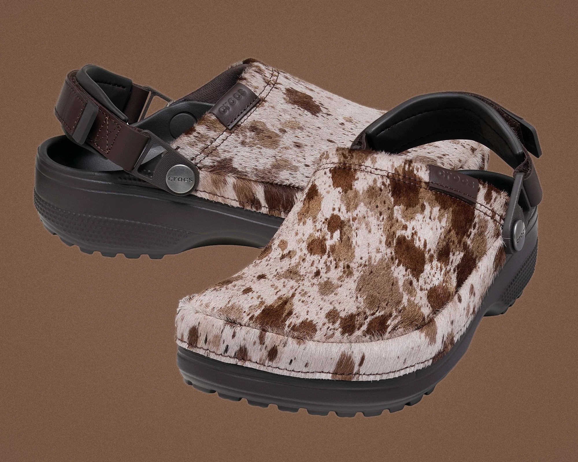 Brown and white speckled fur-textured Crocs with dark brown adjustable heel straps on a brown background.
