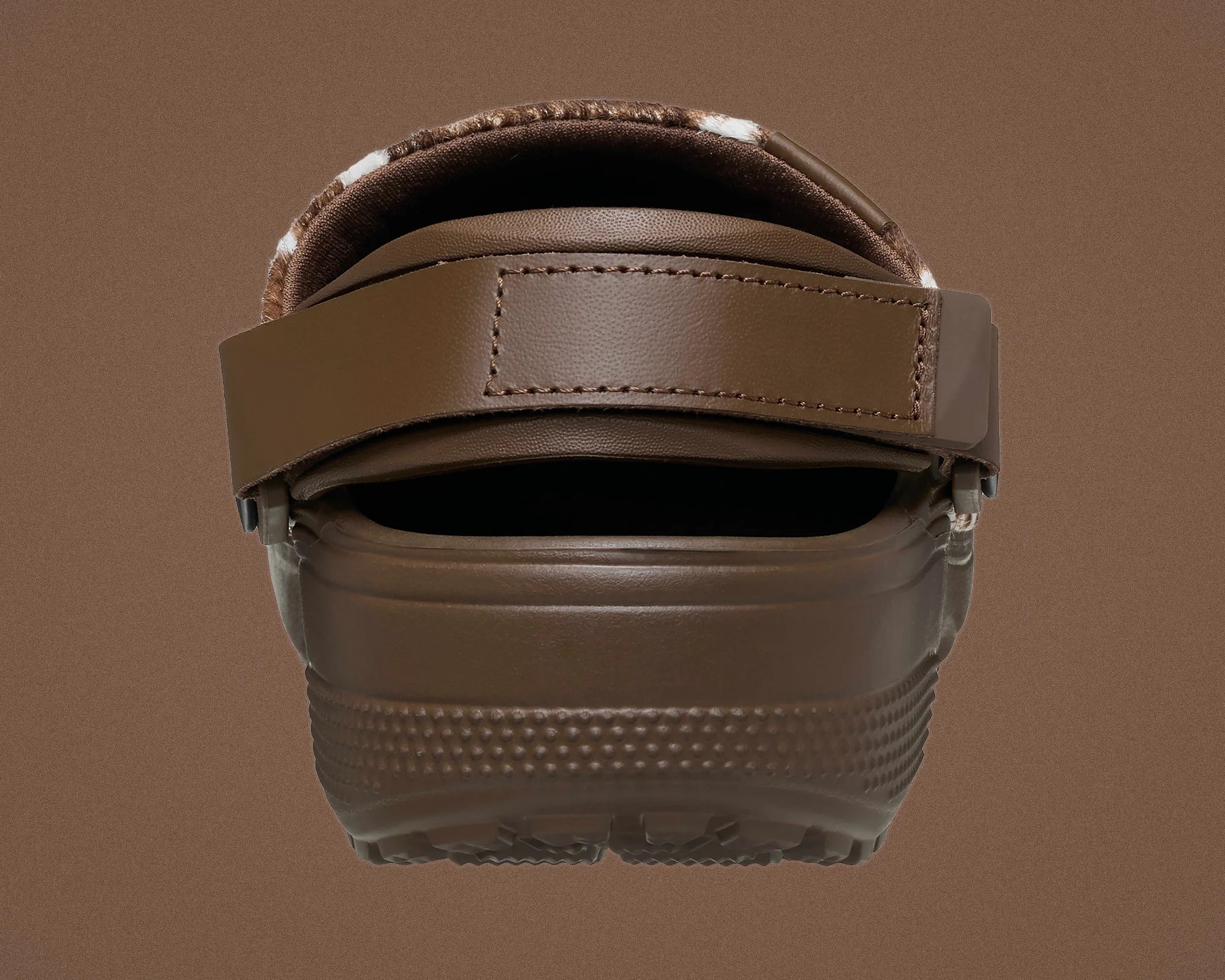 Brown rubber clog with adjustable strap and textured sole viewed from the back.