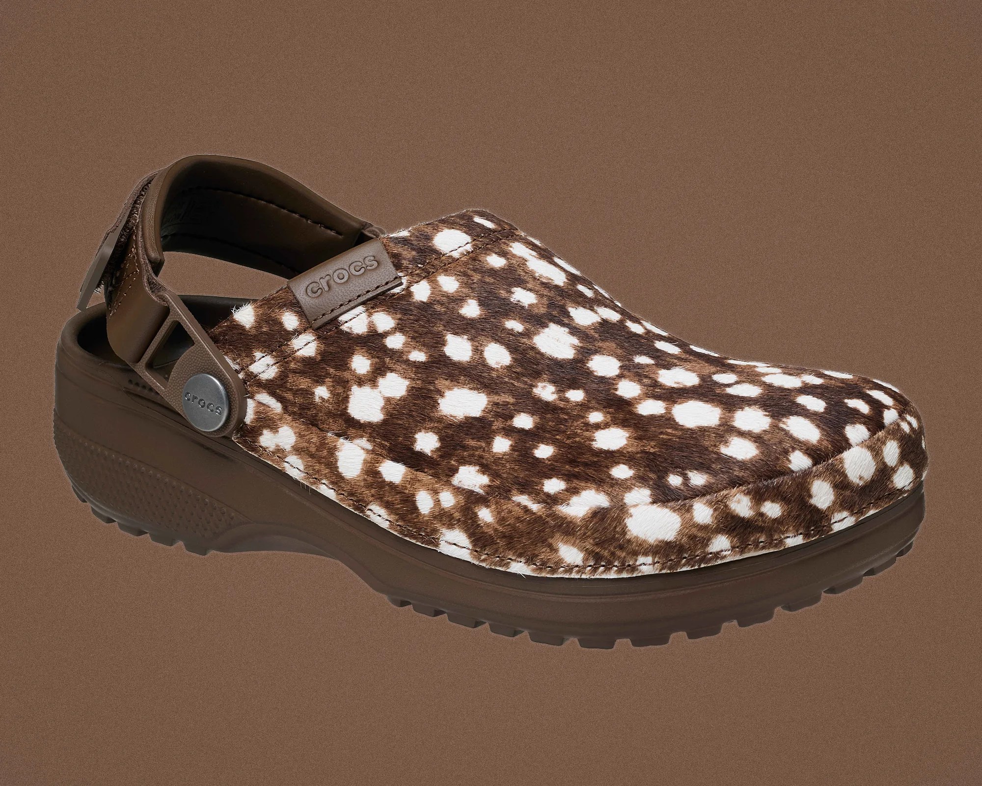 Brown Crocs clog with white spotted fur-like upper and adjustable heel strap.