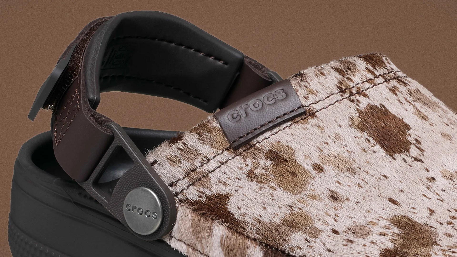Close-up of a Crocs clog with brown and white spotted fur upper and black adjustable heel strap.
