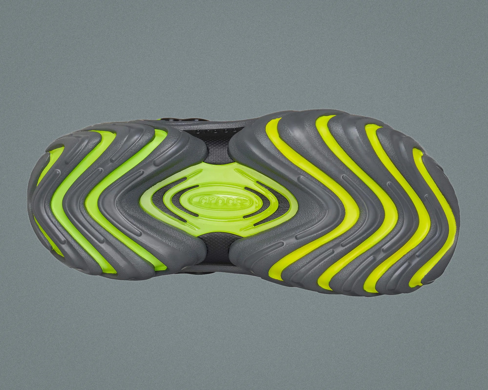 Sole of a gray and neon green Crocs shoe with wavy tread patterns.
