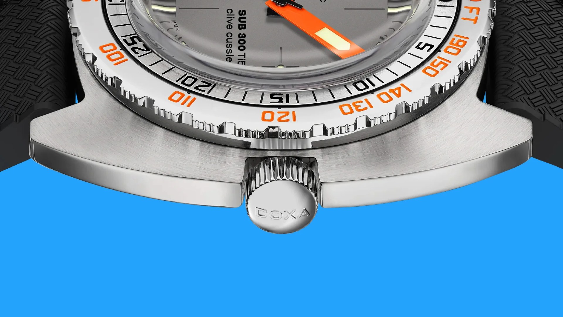 Close-up of a stainless steel watch case with a knurled crown engraved with "DOXA" and an orange-accented bezel.
