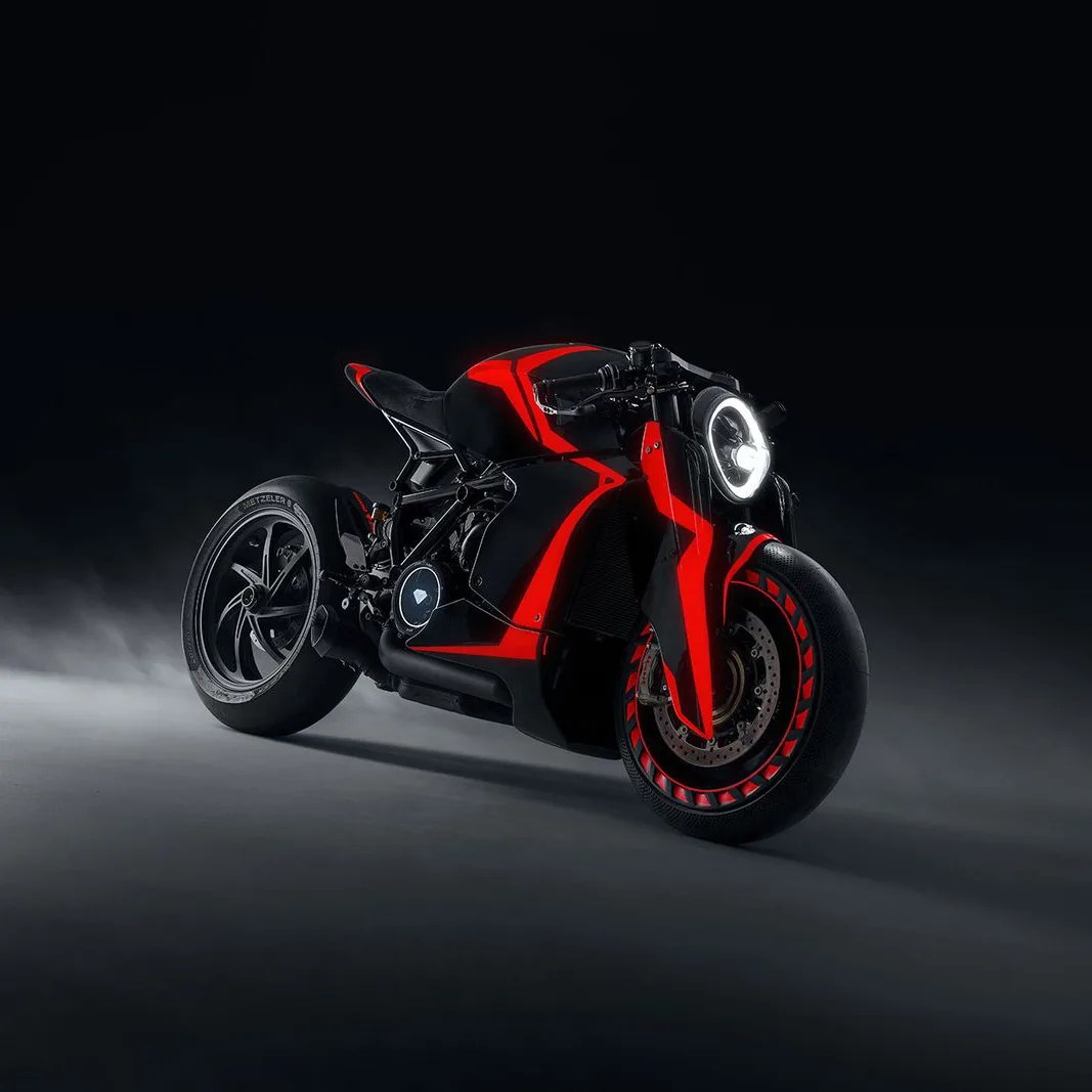 Black and red futuristic motorcycle with illuminated circular headlight on a dark background.