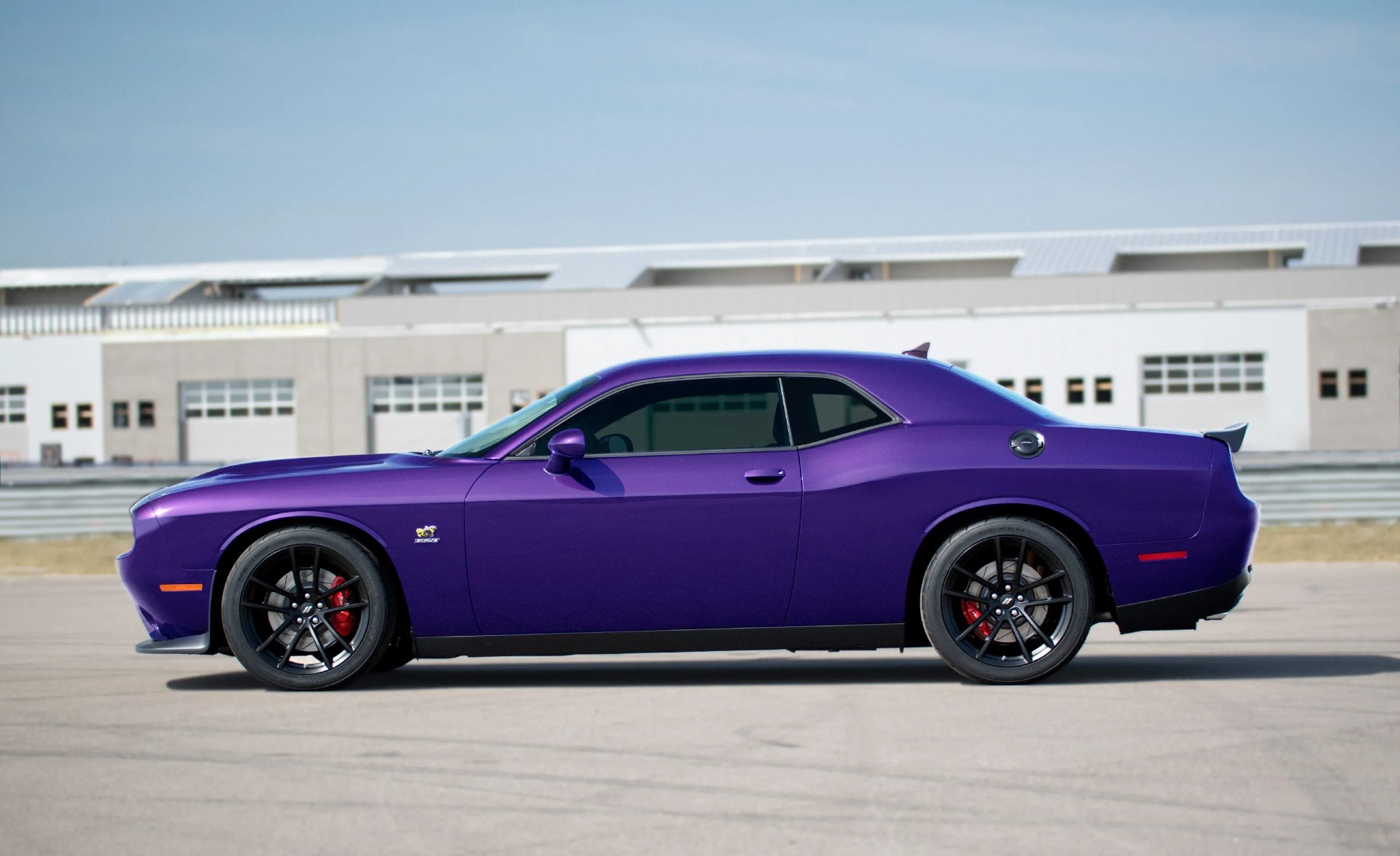 Purple Dodge Challenger SRT muscle car with black wheels and red brake calipers parked on pavement.