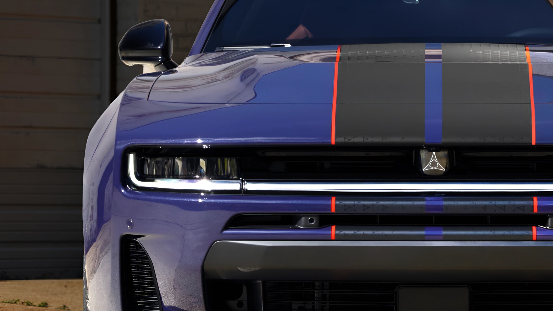 Front view of a purple car with black and orange racing stripes and a distinctive emblem on the grille.
