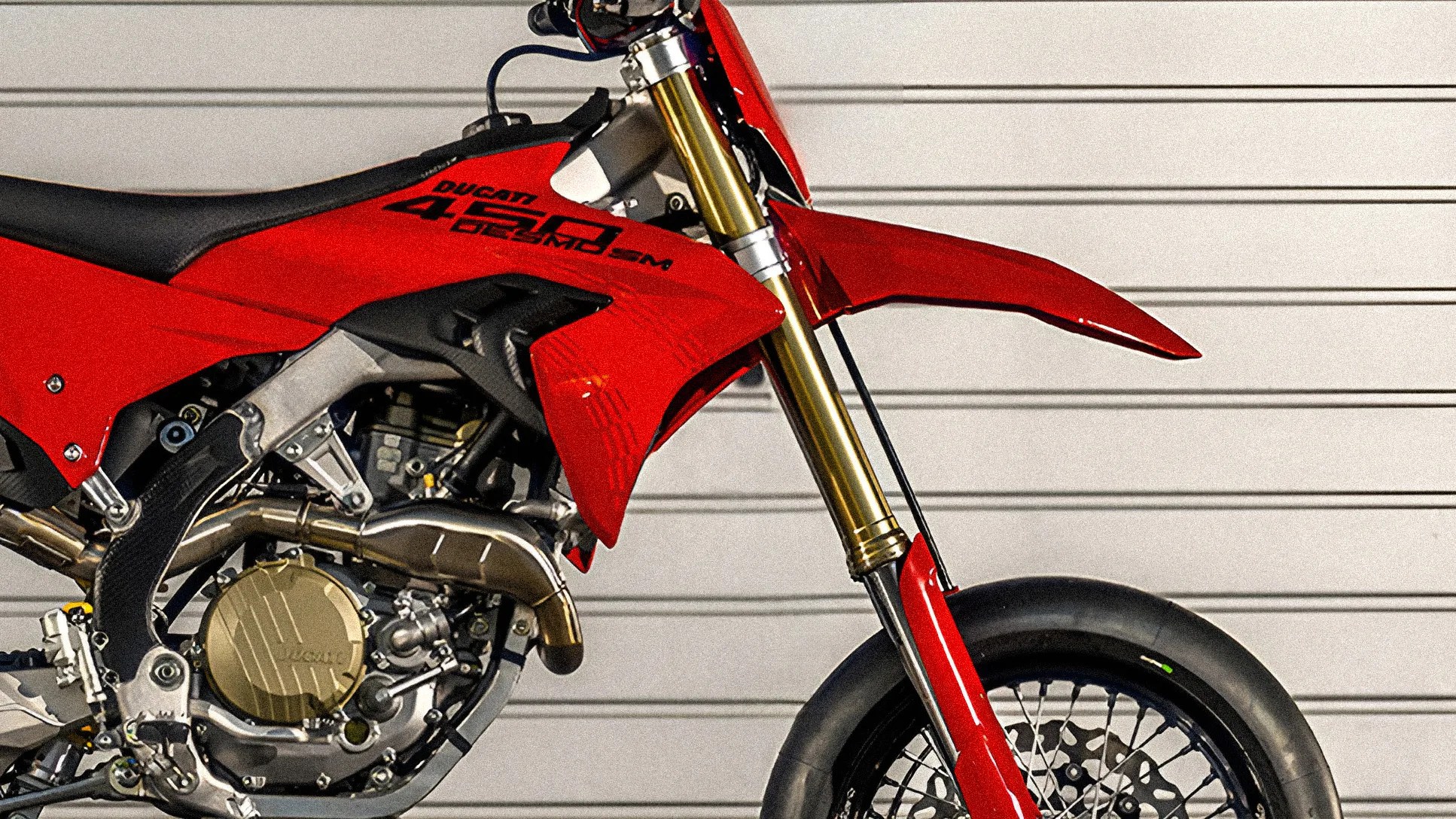 Close-up of red Ducati 450 Desmo SM motorcycle front and engine with gold suspension forks and black tire.