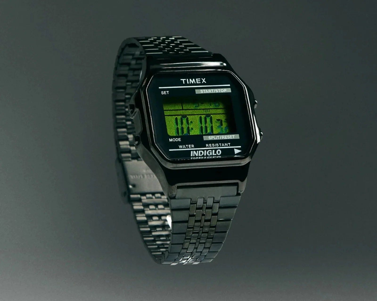 Black Timex digital wristwatch with metal link band and green backlit display showing time 10:10.