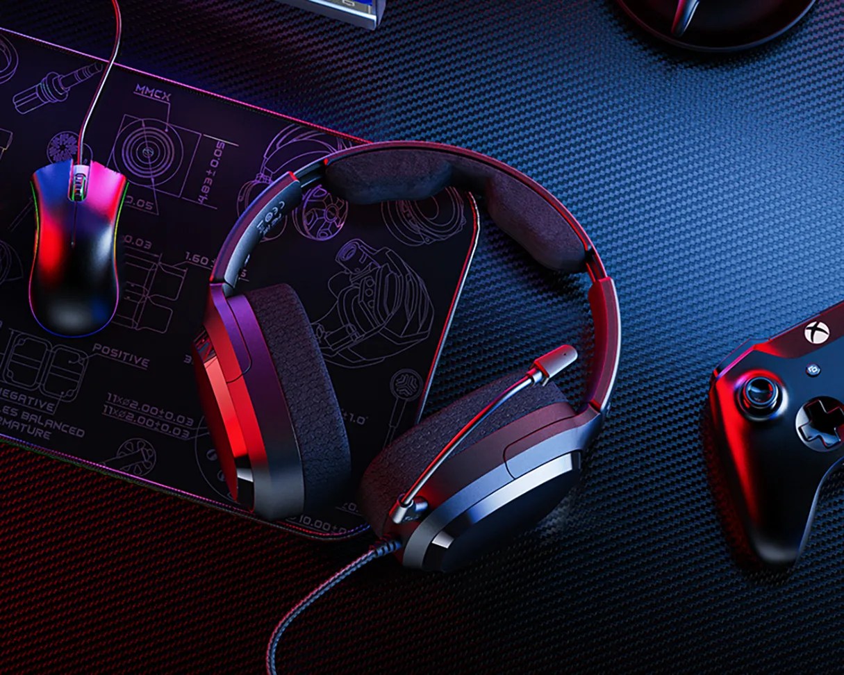 Black gaming headset with a microphone on a carbon fiber surface next to a wired mouse and Xbox controller.