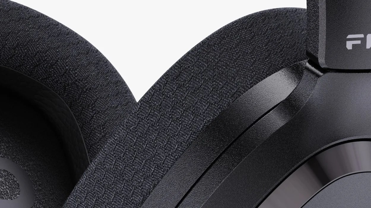 Close-up of black over-ear headphone ear cushions with textured fabric and matte plastic frame.