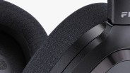 Close-up of black over-ear headphone ear cushions with textured fabric and matte plastic frame.