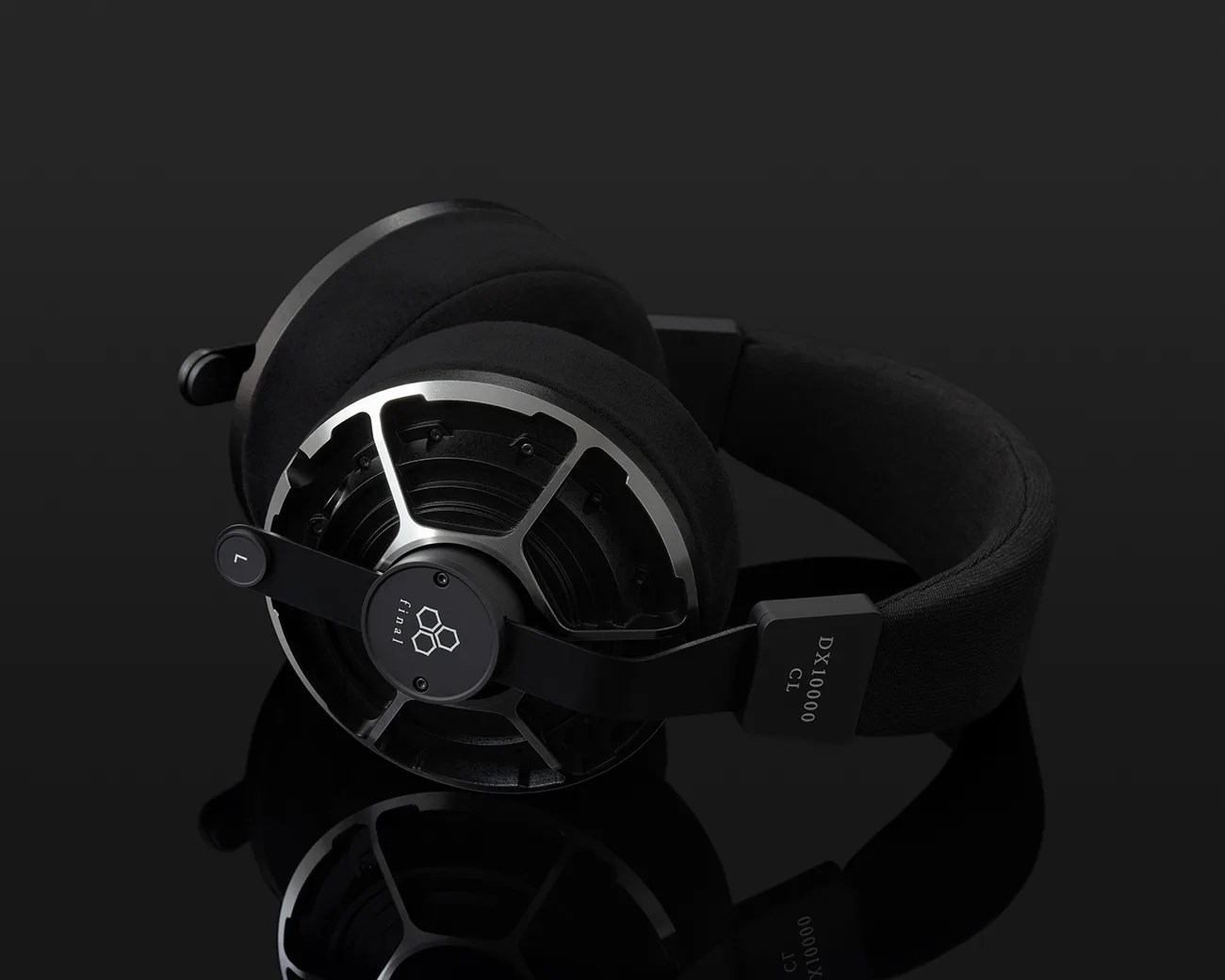 Black over-ear headphones with metal frame and fabric headband labeled "DX10000 CL" on a reflective black surface.