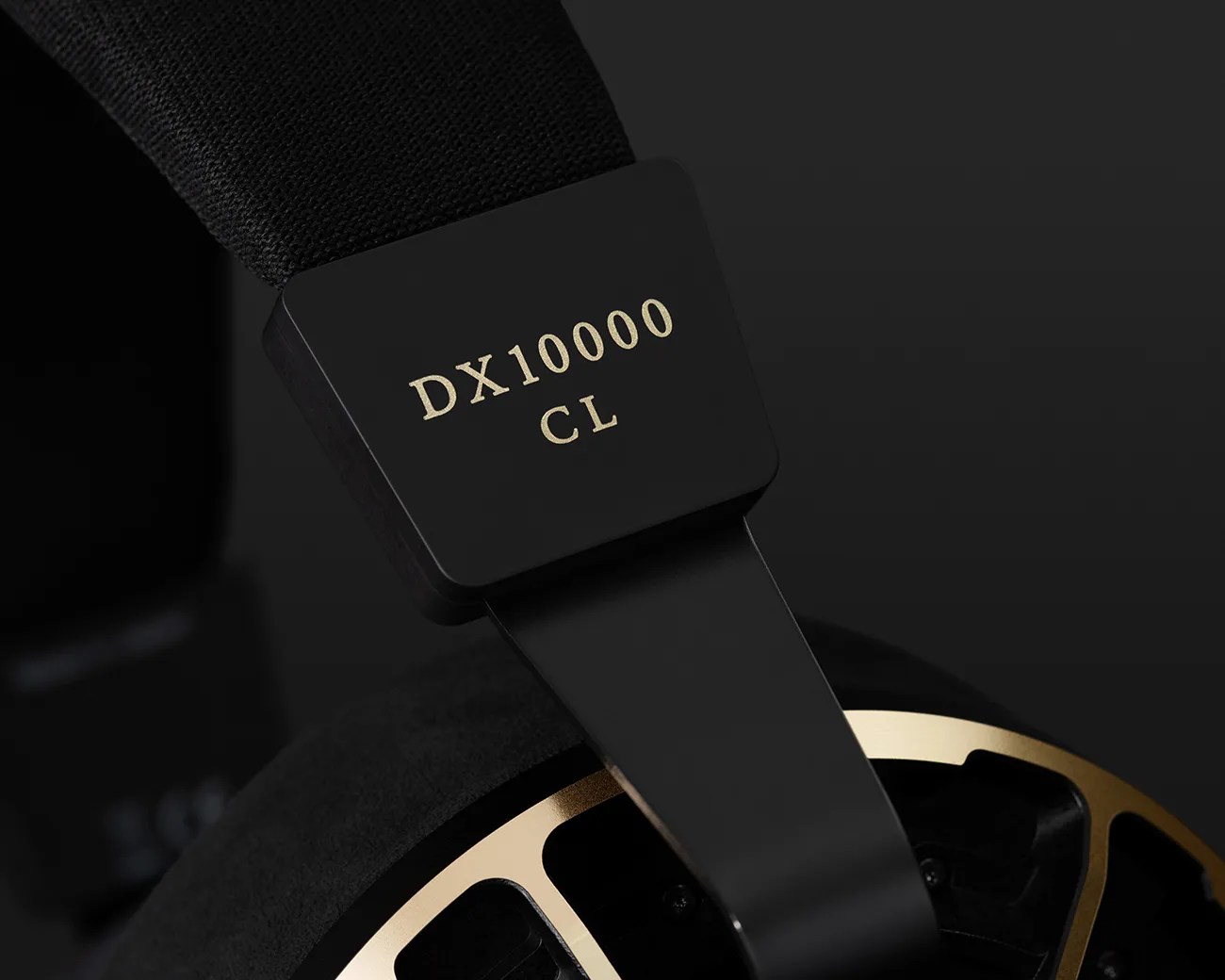 Close-up of black headphone arm with gold text "DX10000 CL" and part of gold-accented ear cup.