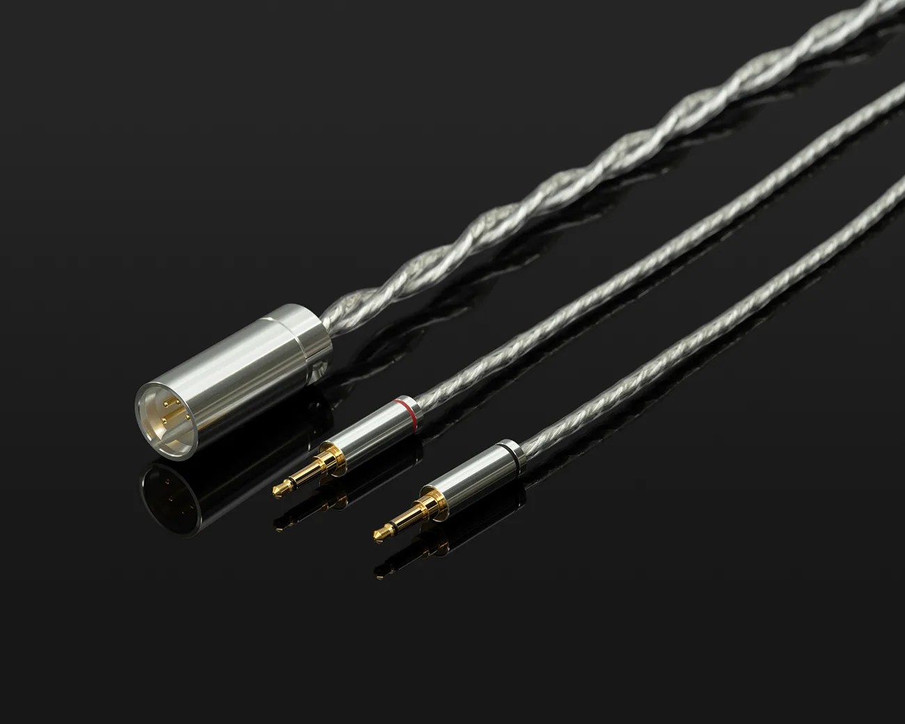 Silver braided audio cable with one XLR connector and two 3.5mm gold-plated plugs on a black reflective surface.