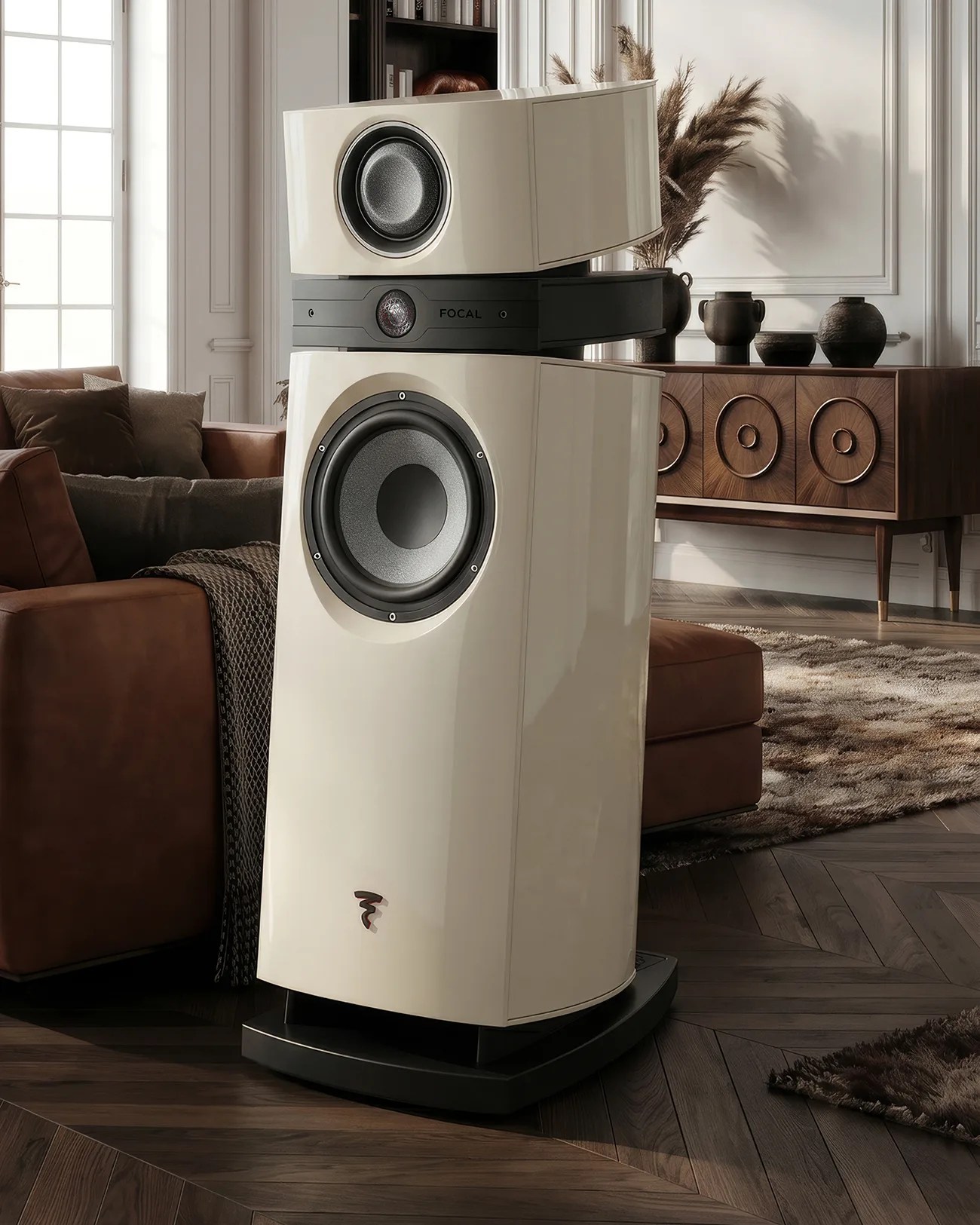 Glossy cream-colored floor-standing speaker with black base and visible drivers in a modern living room.