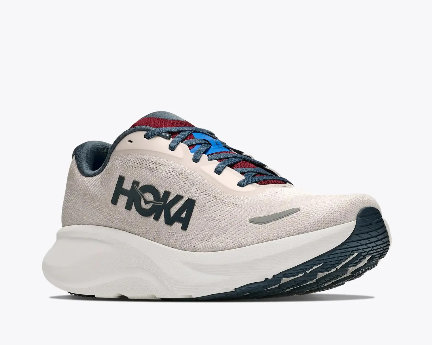 Light beige HOKA running shoe with dark blue laces, red tongue, and thick white sole with black tread.