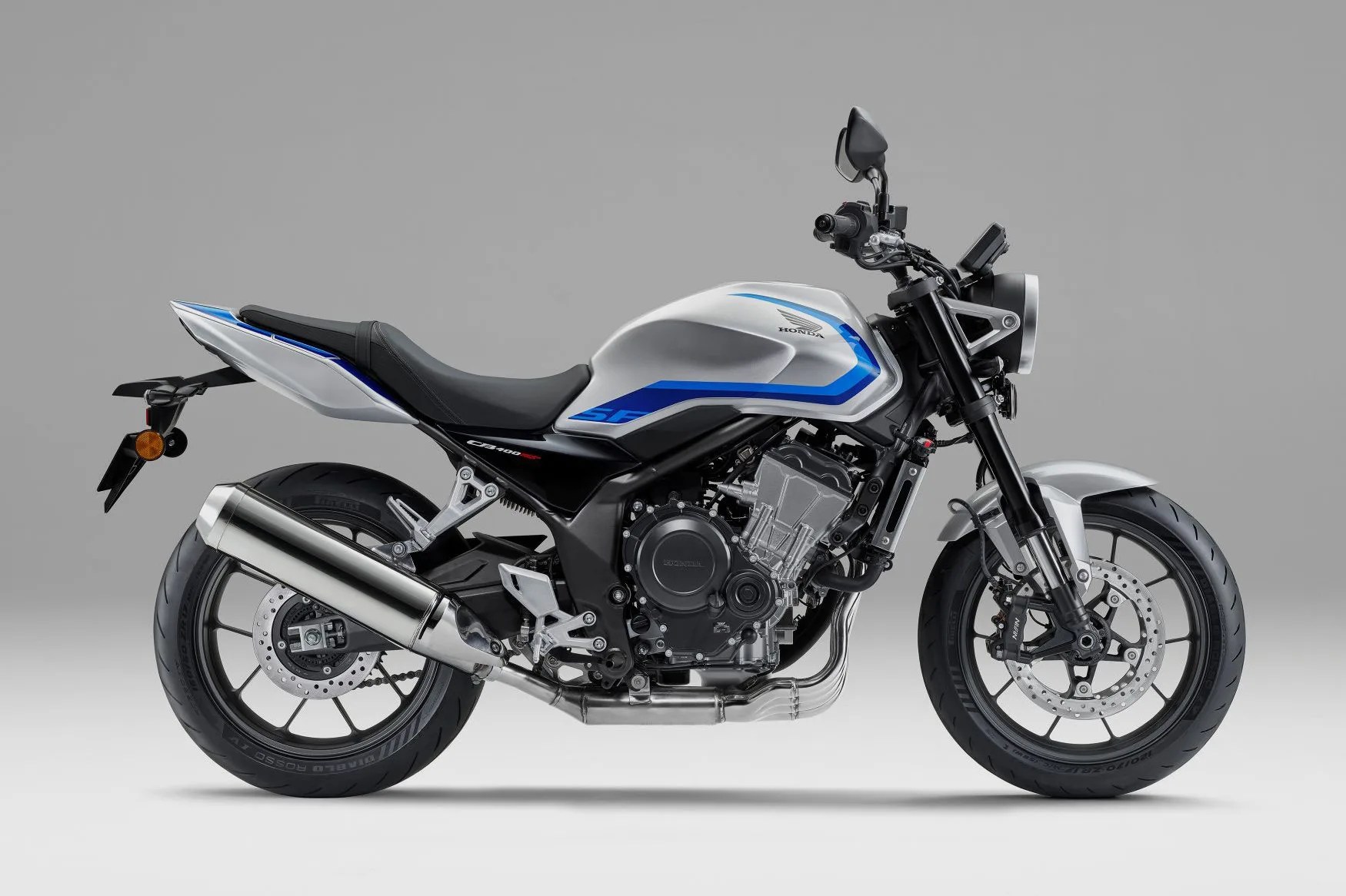 Silver and blue Honda CB400SF motorcycle with black seat and exhaust pipe on gray background.