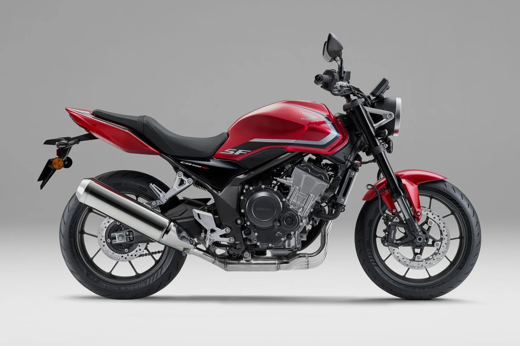 Red and black Honda CB400SF motorcycle with silver exhaust and black tires on a gray background.