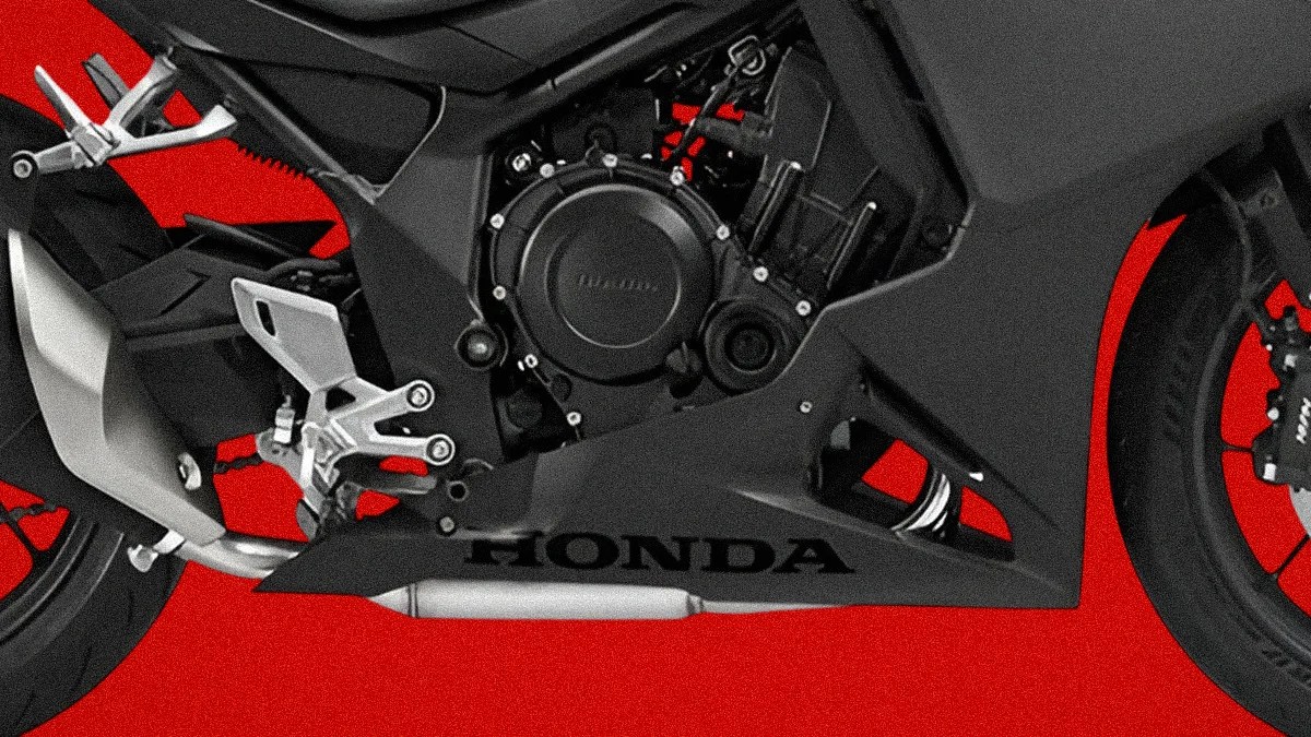 Close-up of black Honda motorcycle engine and exhaust against a red background.