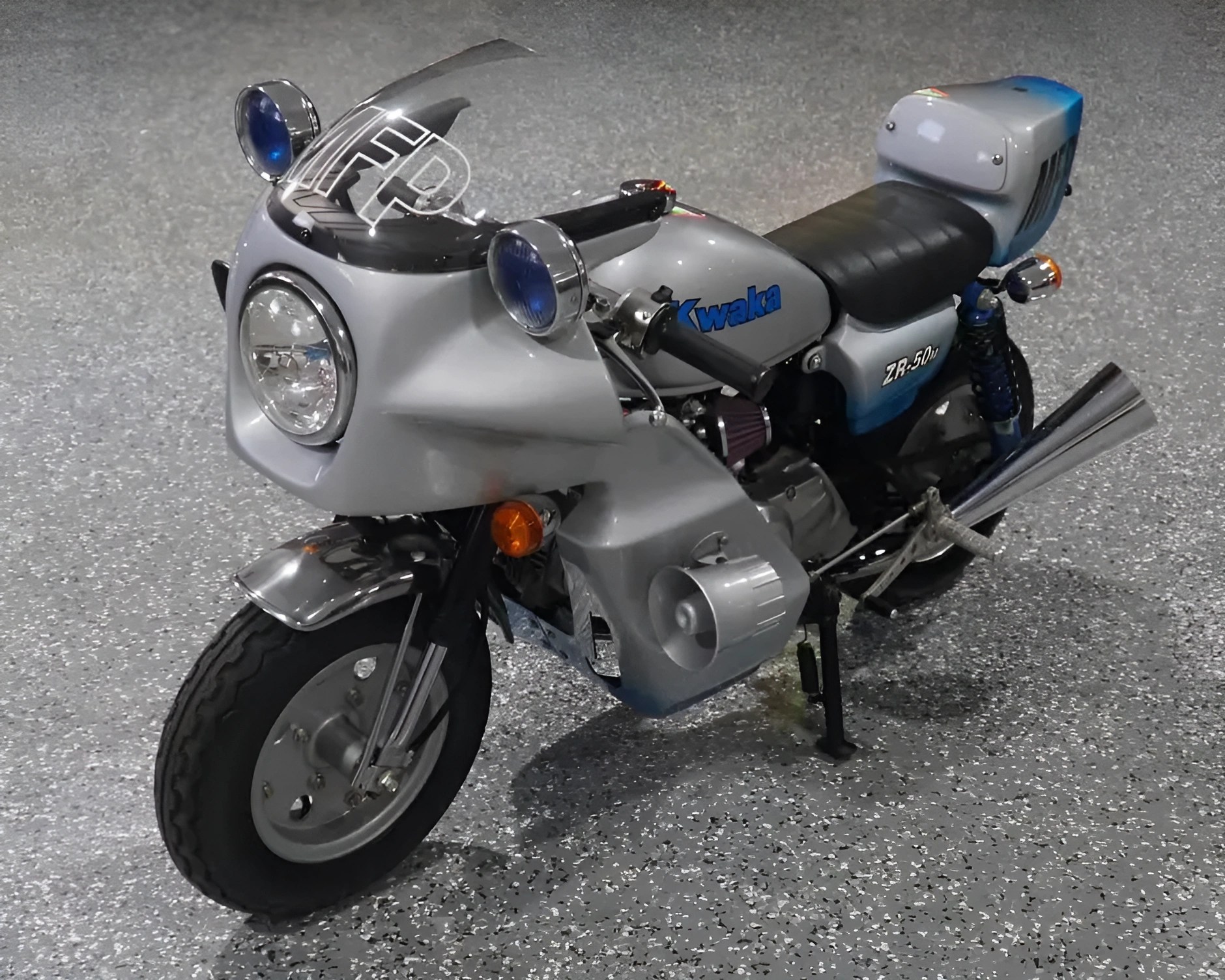 Silver and blue Kawasaki ZR-50 motorcycle with black seat and front fairing on speckled gray floor.