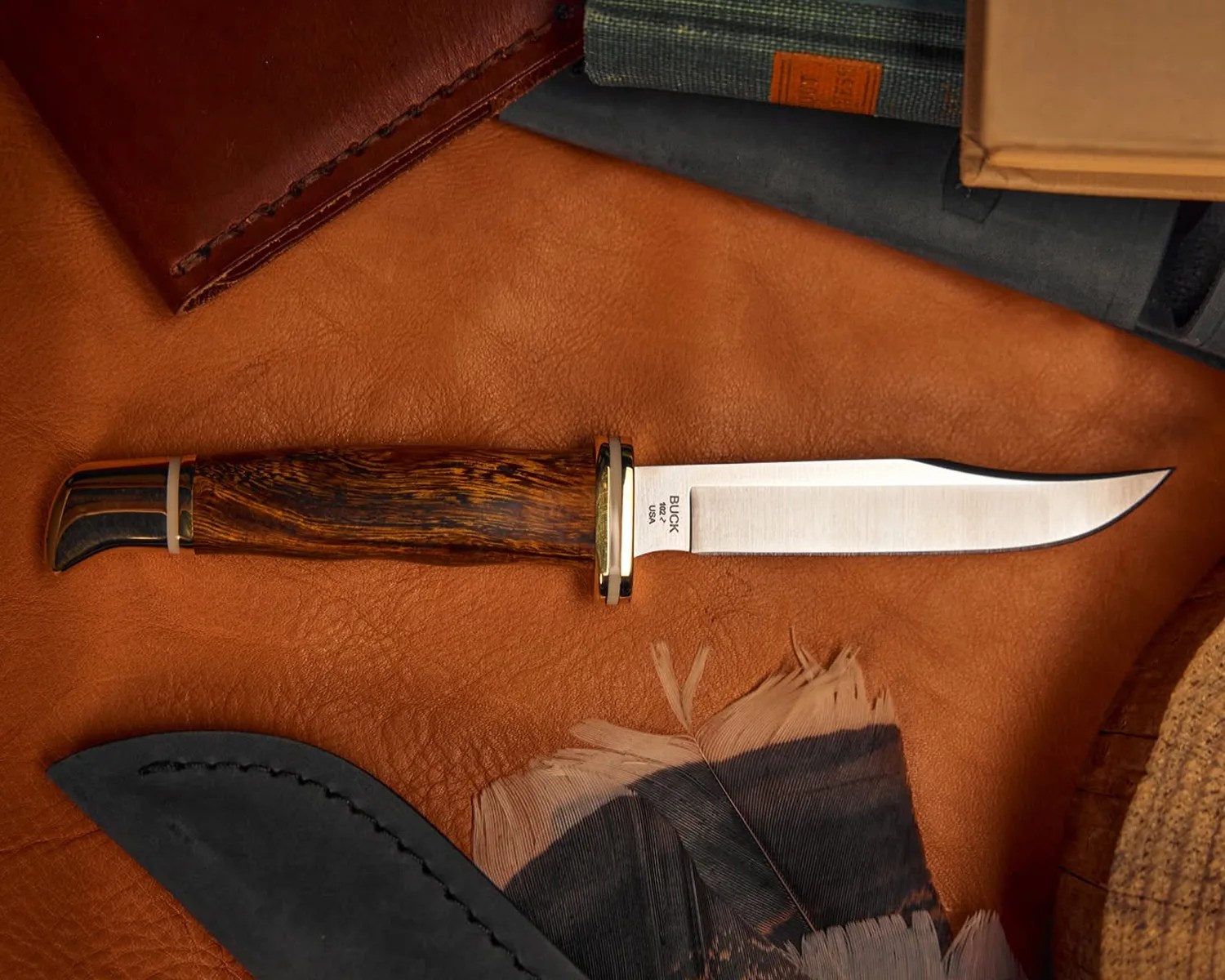 Fixed-blade Buck knife with wooden handle and brass guard on a brown leather surface.