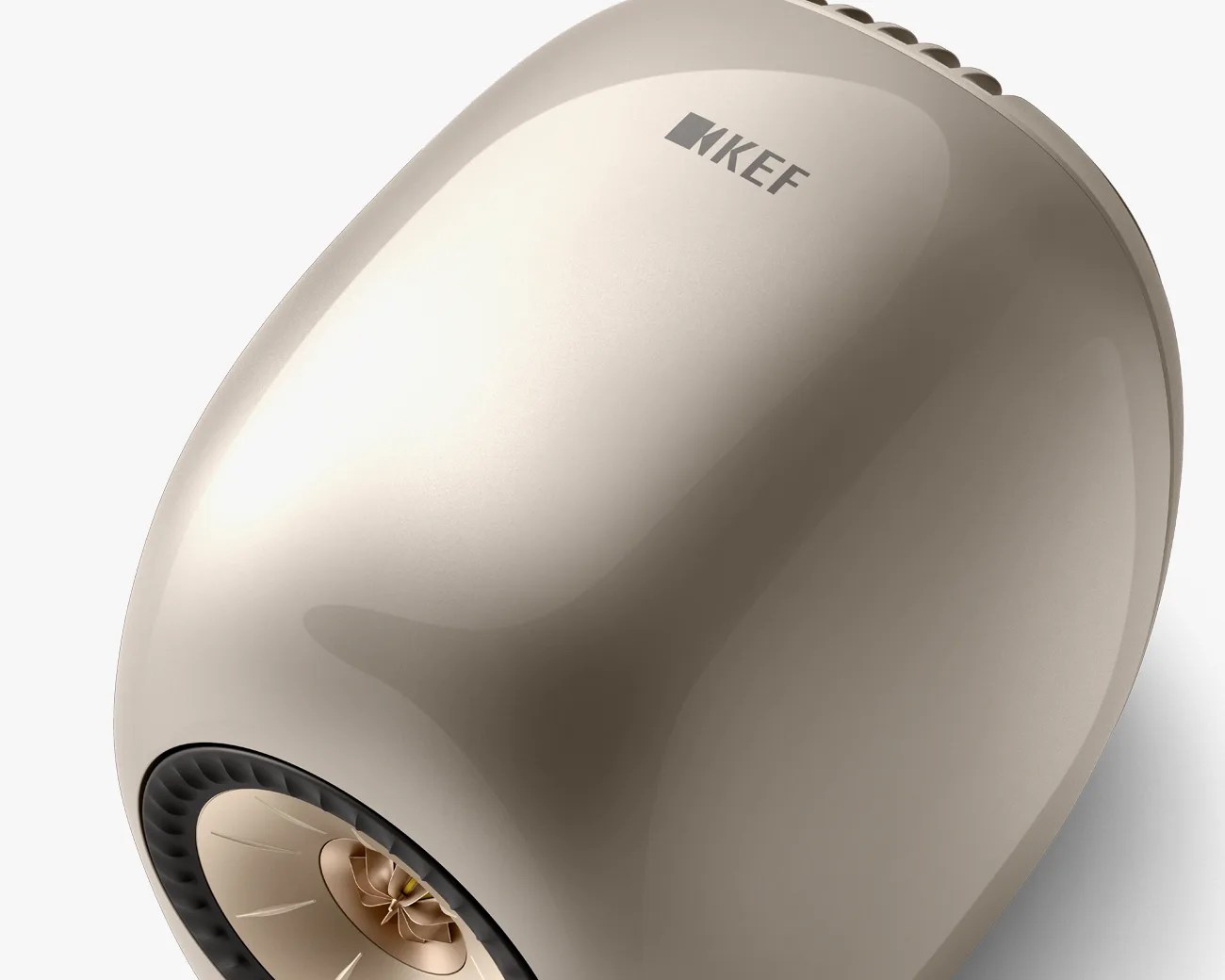 Glossy beige KEF speaker with a central gold-colored cone and black ring around it.