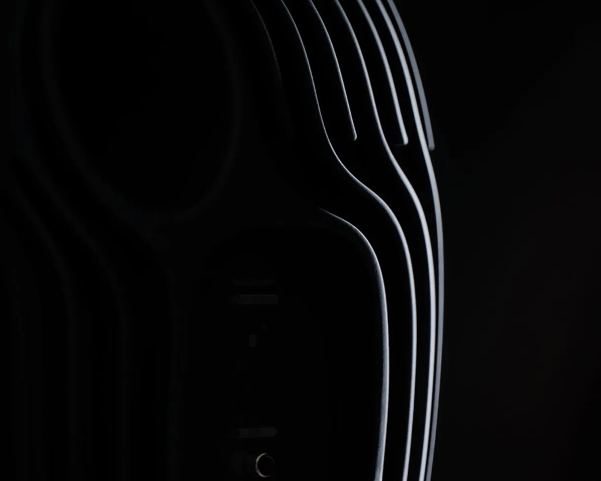 Close-up of a black object with curved, ribbed edges highlighted by soft lighting against a dark background.