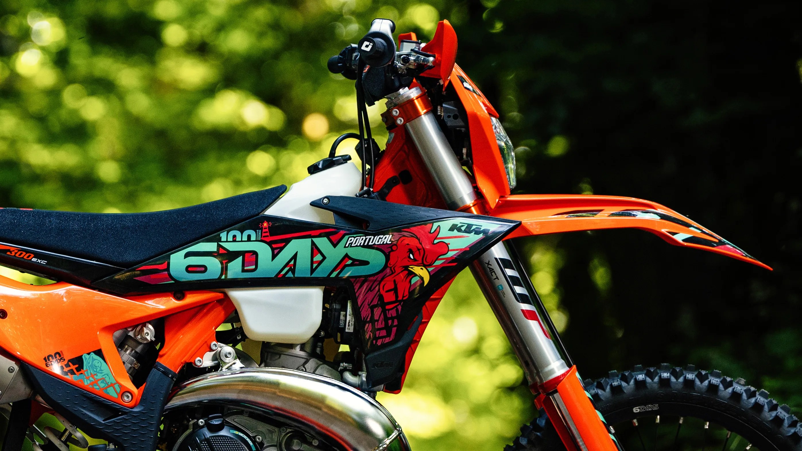 Orange KTM dirt bike with black seat and "6 Days Portugal" graphic on the side panel.
