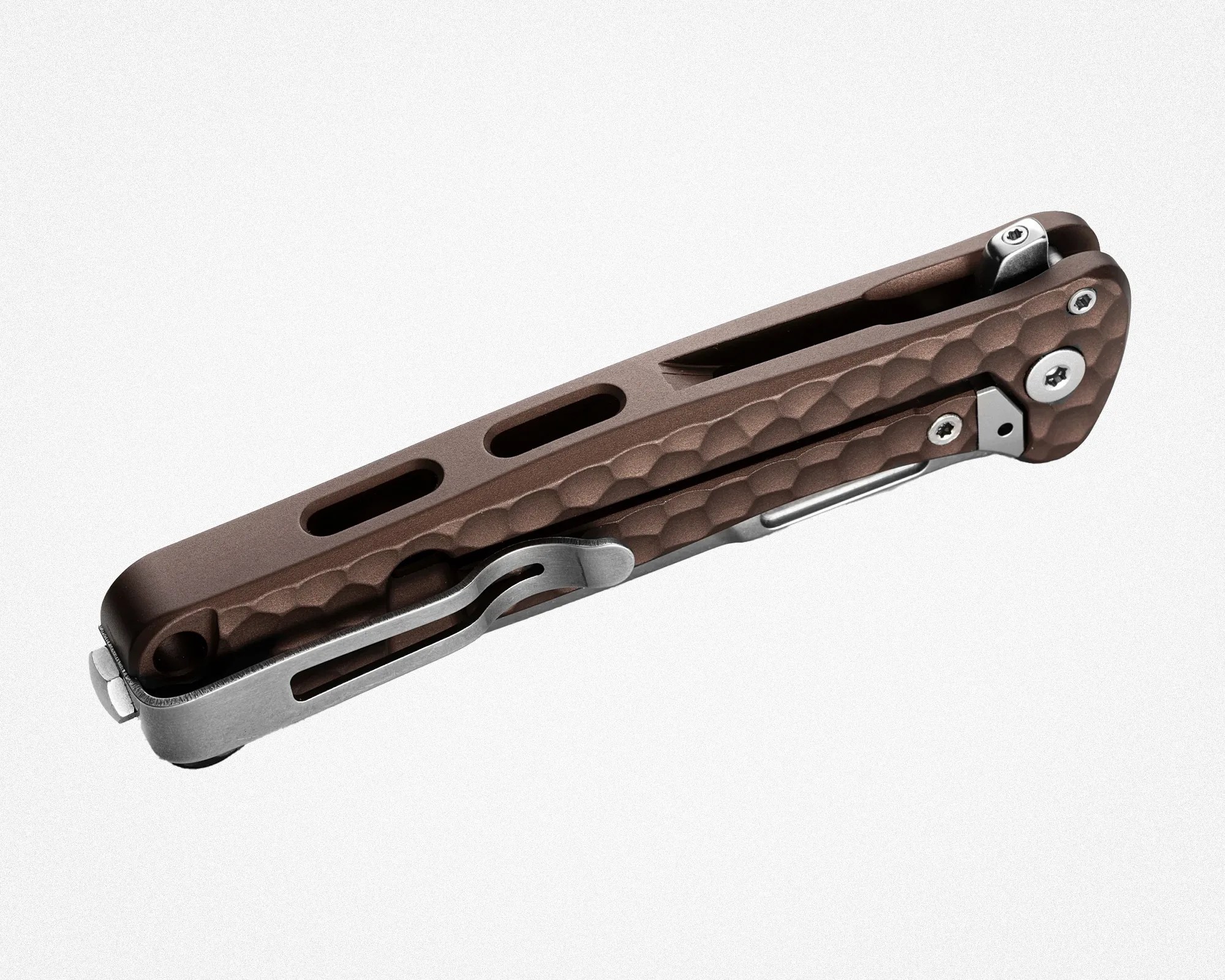Brown textured folding knife handle with metal clip and screws on a white background.