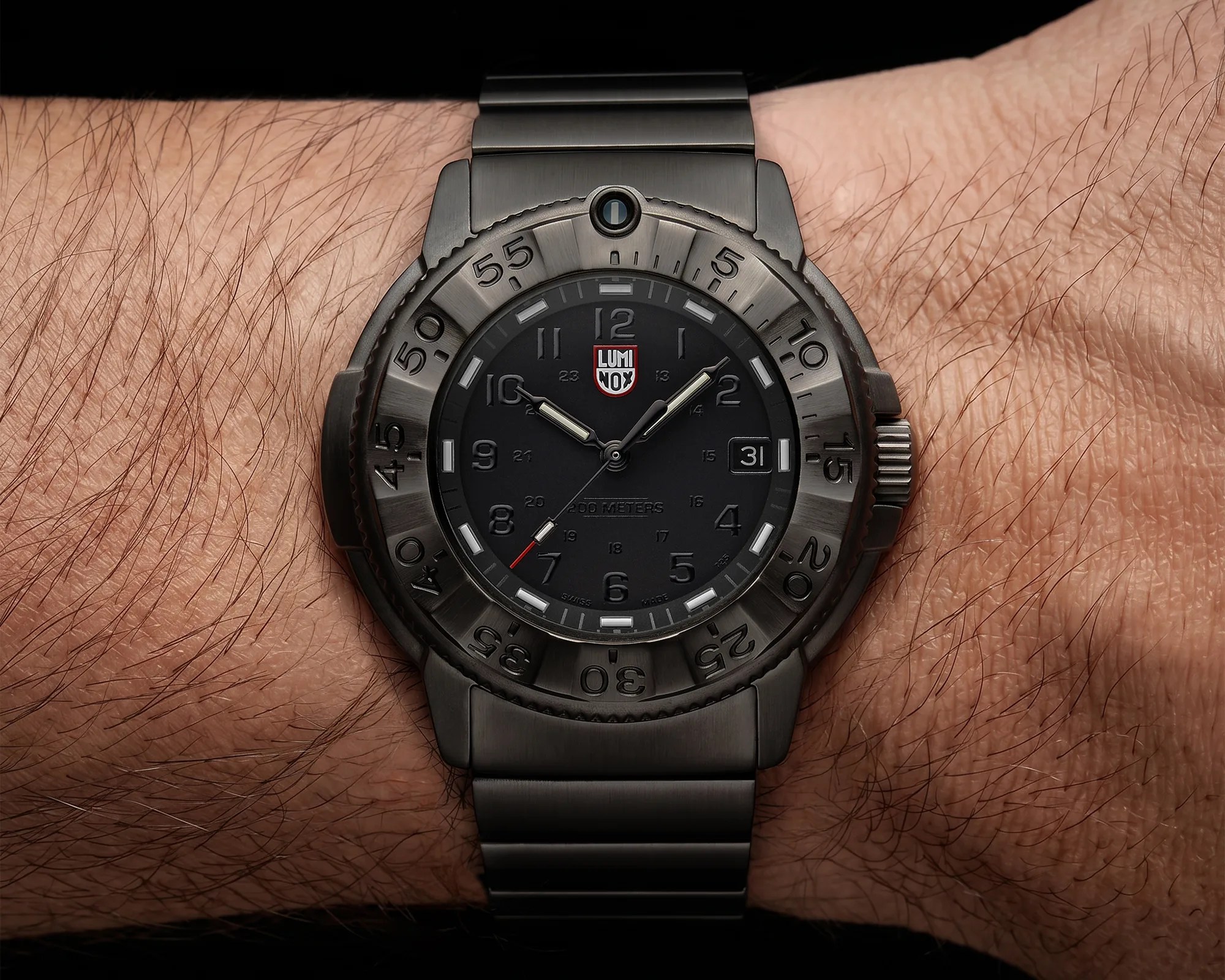 Black Luminox wristwatch with a metal band and rotating bezel worn on a wrist.