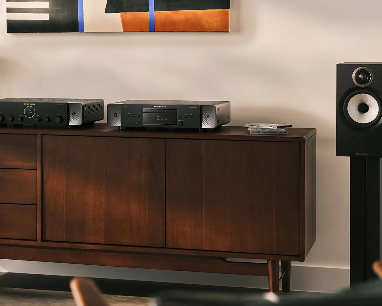 Dark wood sideboard with Marantz audio equipment and a black speaker on a stand beside it.
