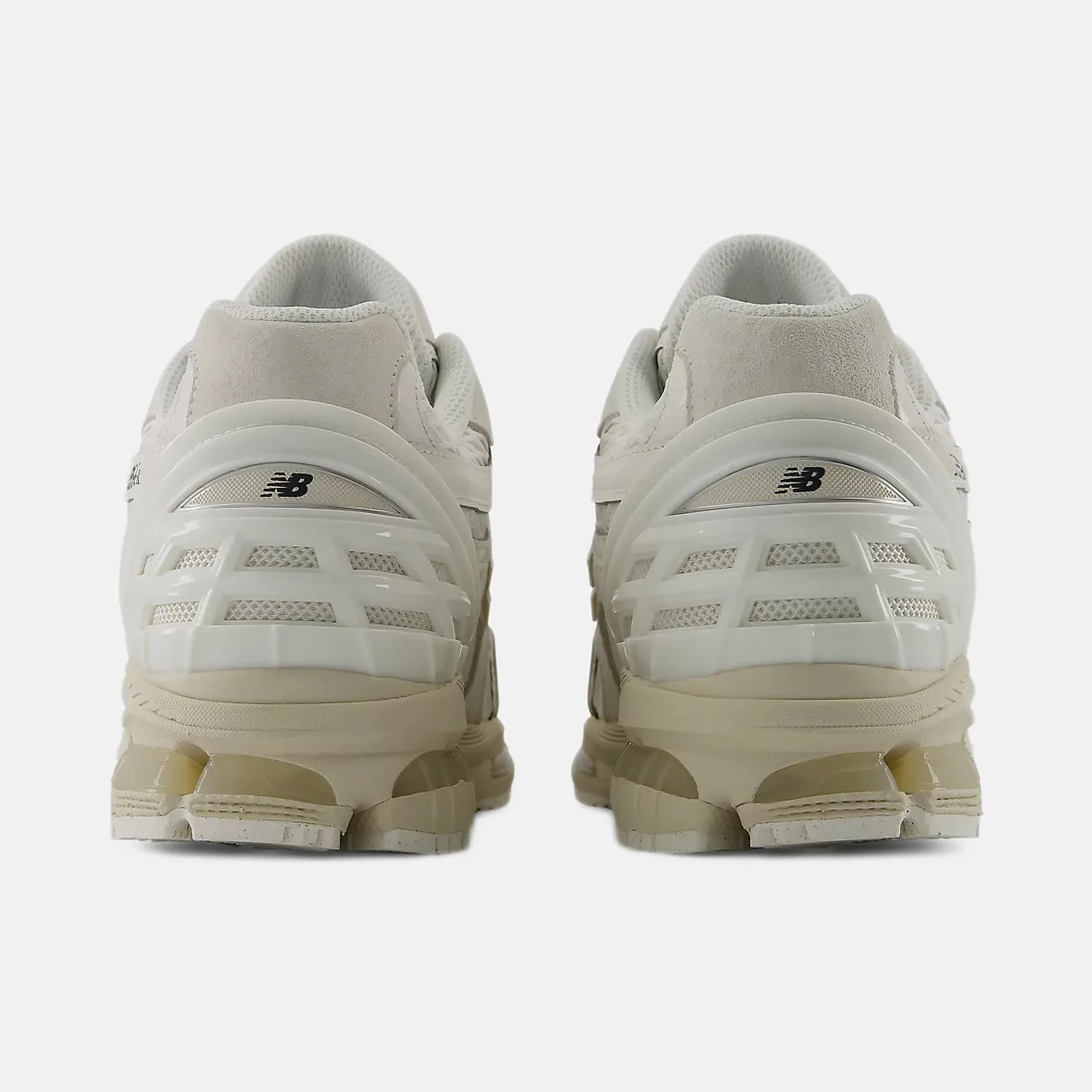 Pair of off-white New Balance sneakers shown from the back with mesh and plastic heel support.