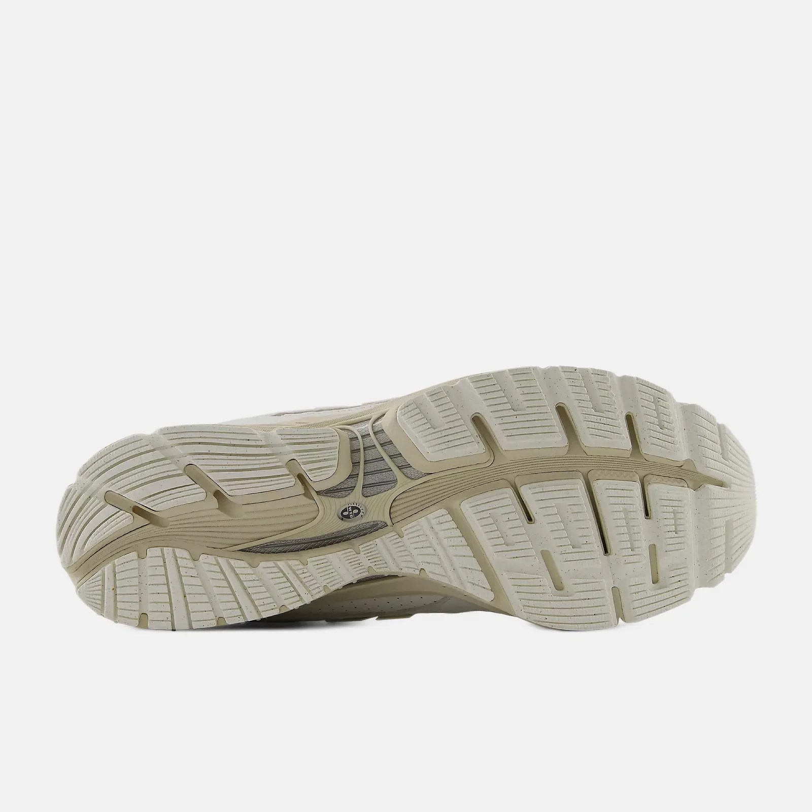 Beige rubber outsole of a sneaker with deep grooves and textured tread pattern.