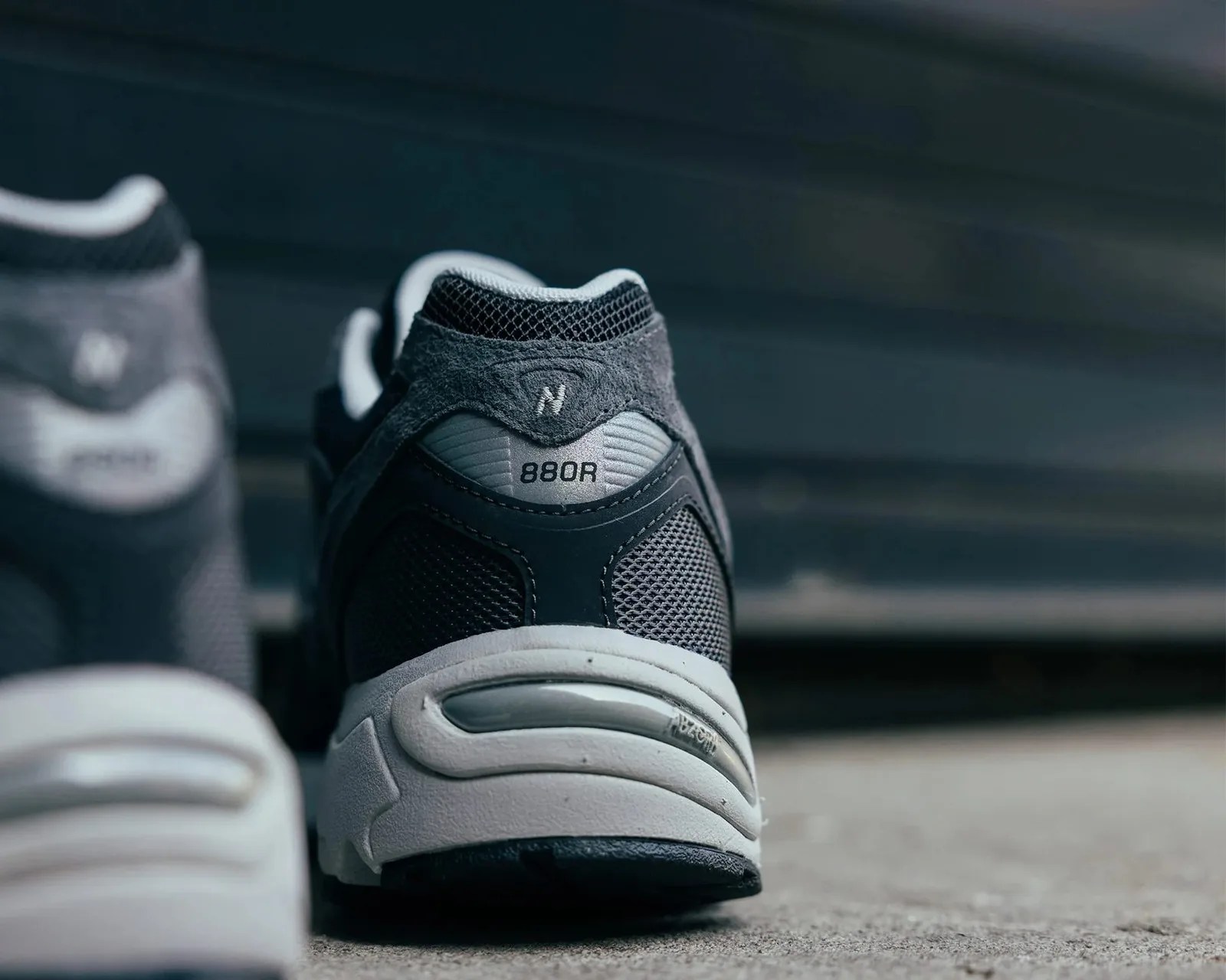 Close-up of the back of a black and gray New Balance 880R sneaker on a concrete surface.