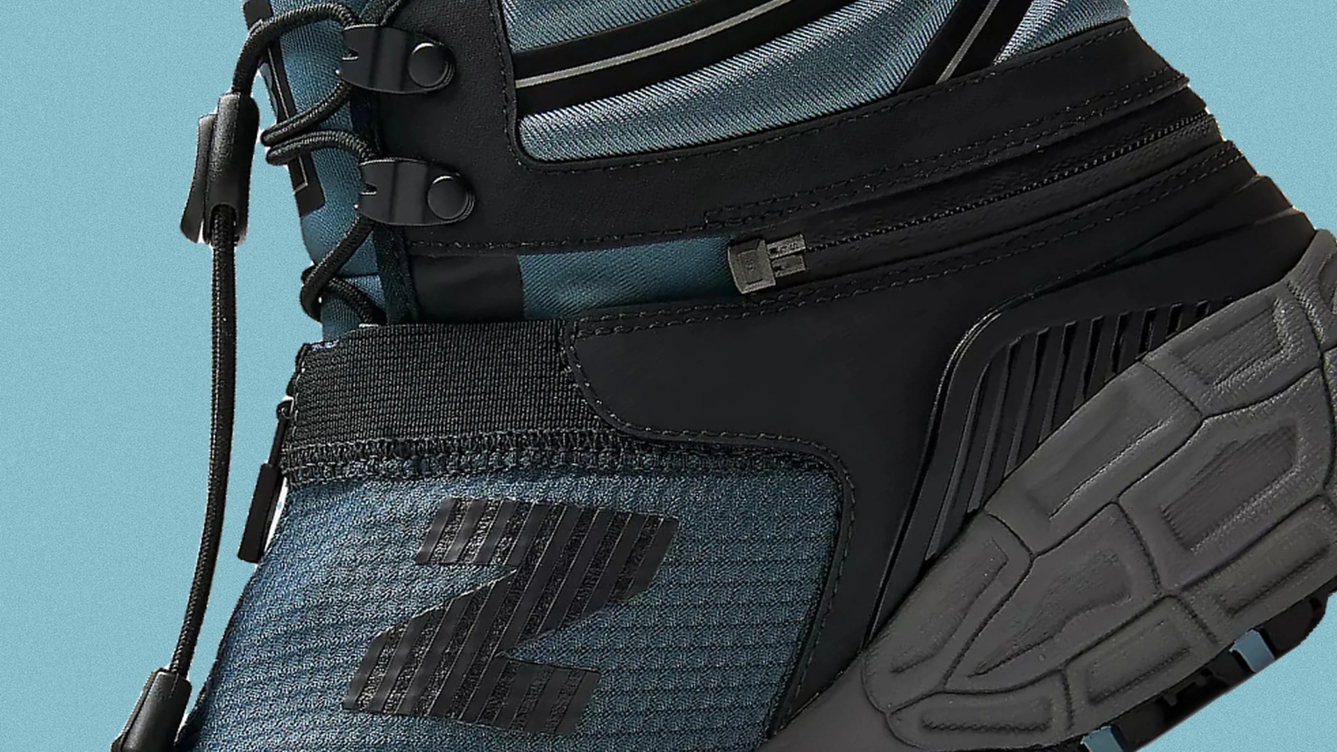 Close-up of a blue and black sneaker with black laces and a textured gray sole.