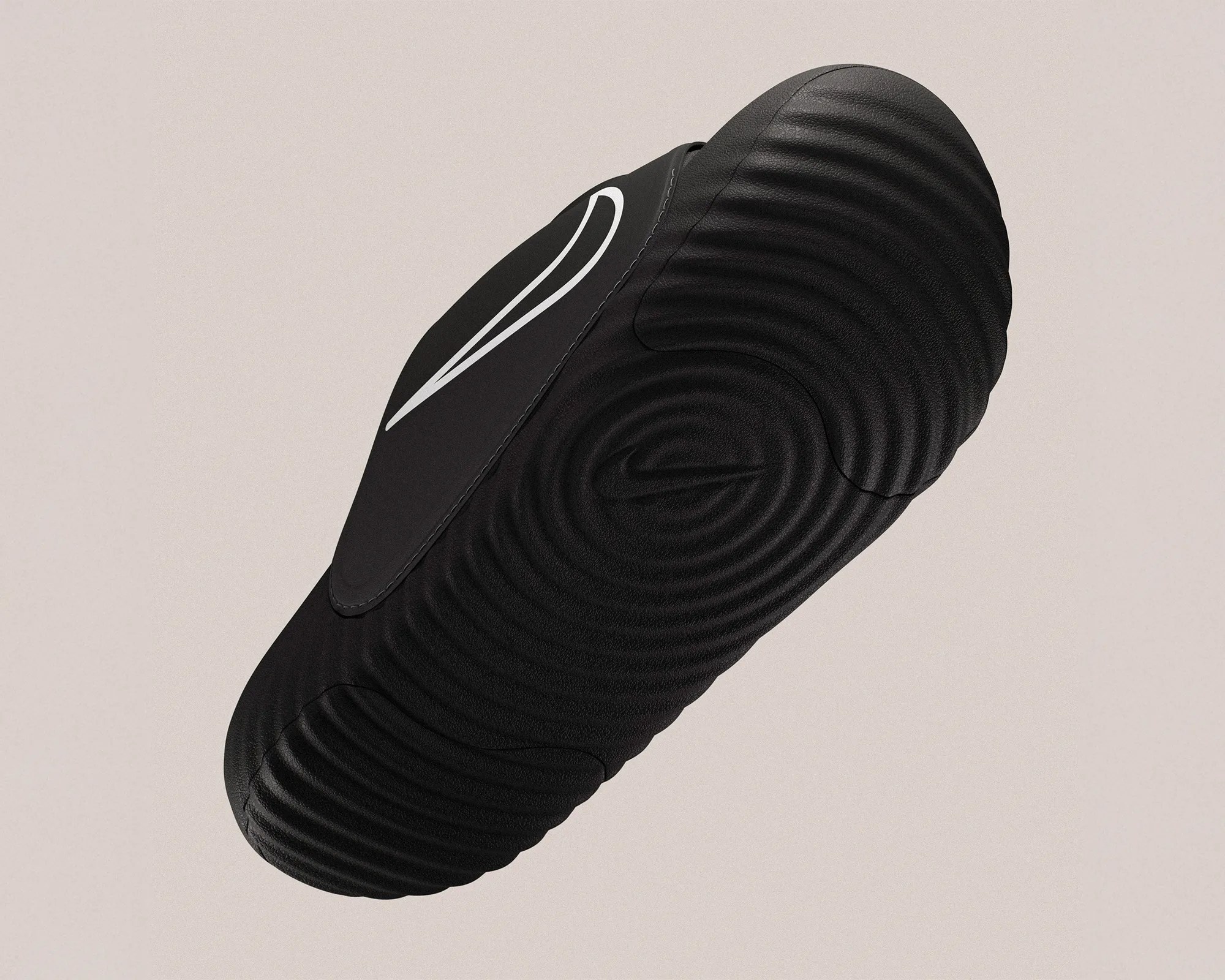 Black Nike shoe sole with circular textured pattern and white swoosh logo on a beige background.