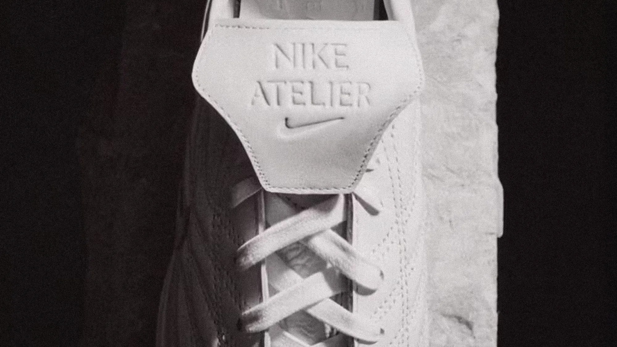 Close-up of white Nike Atelier sneaker tongue with embossed logo and laces.